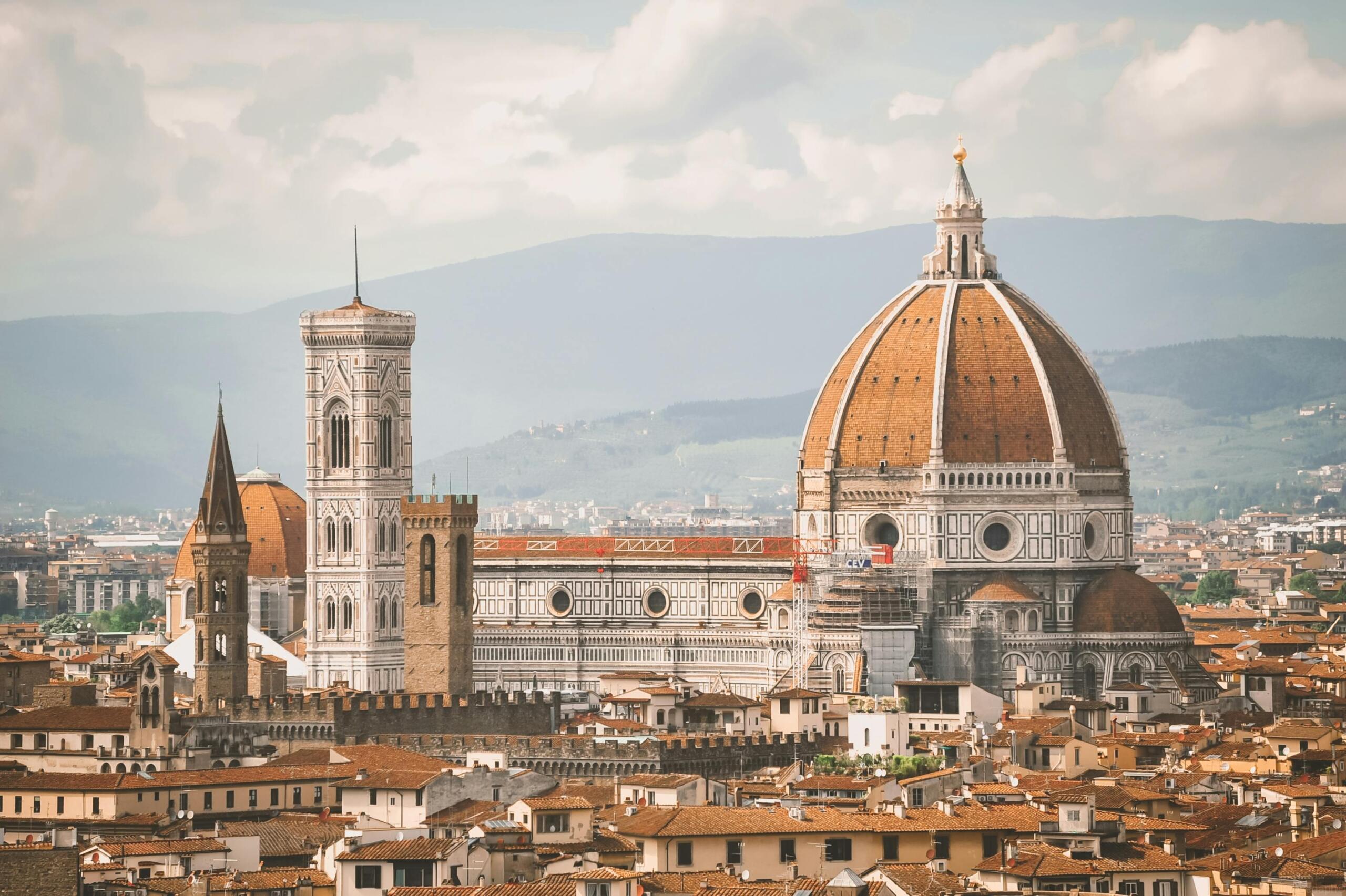 The Duomo of Florence, with its iconic red-tiled dome and intricate marble façade, standing majestically under a bright sky as a symbol of Renaissance architecture and Italian heritage.