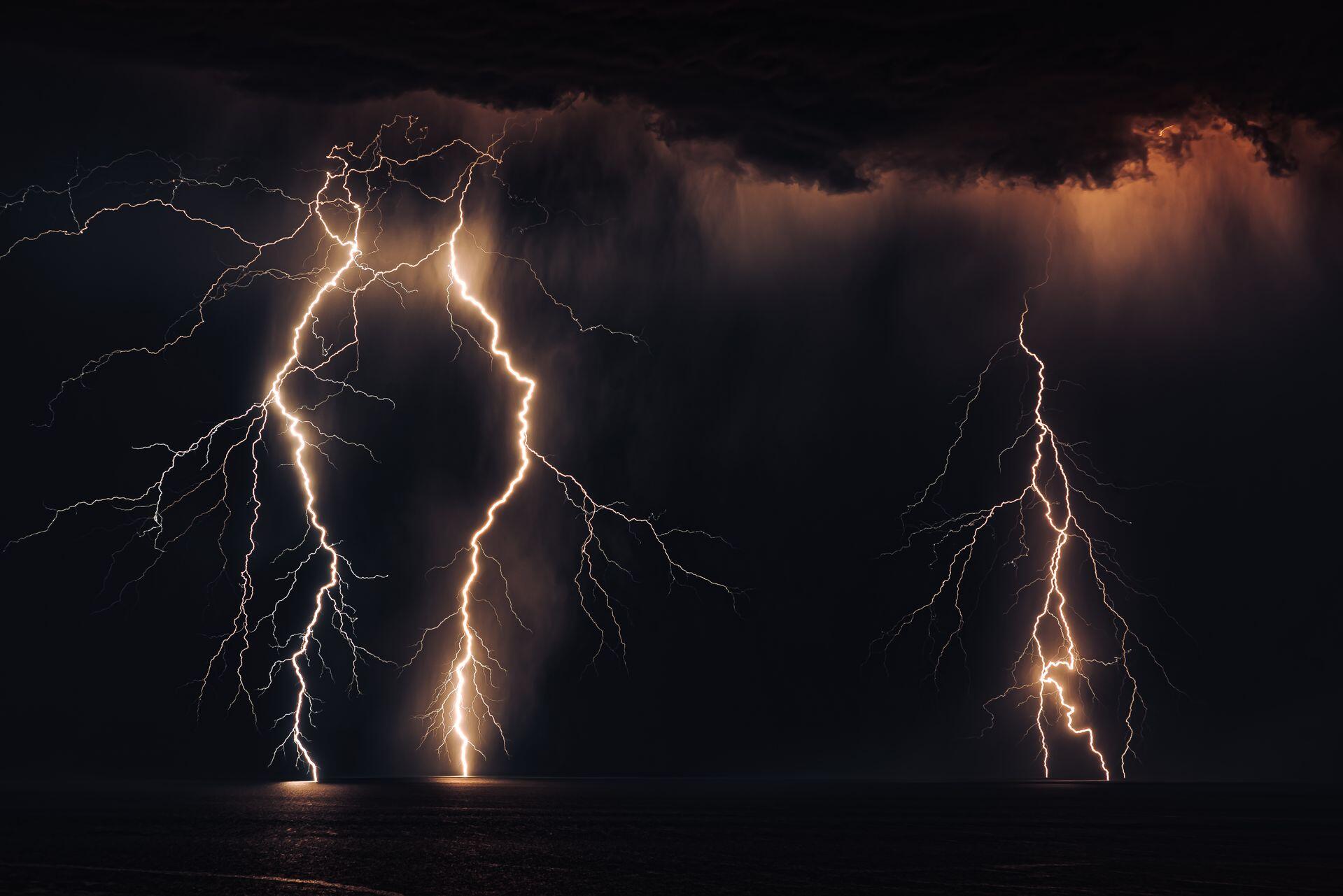 lightning strikes over the ocean at night