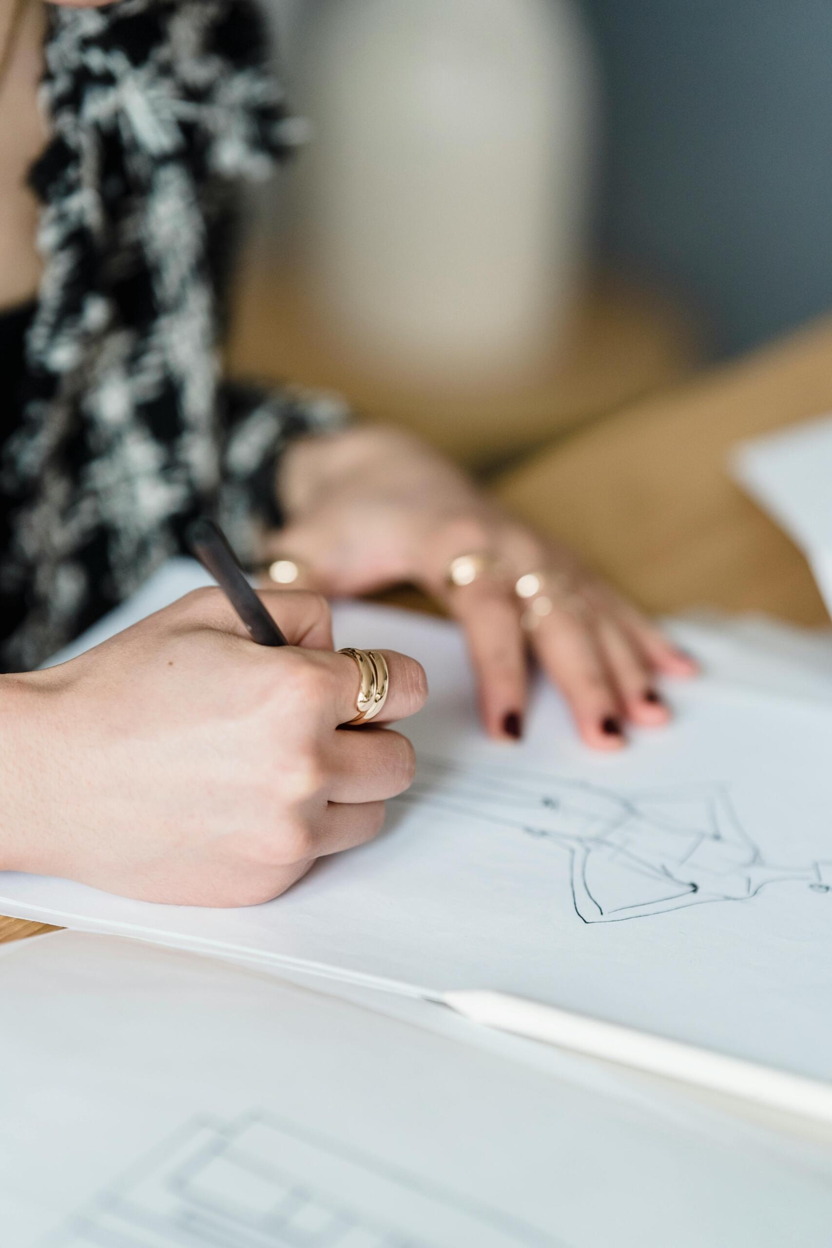 Close-up of a woman focused on drawing, holding a pencil and sketching carefully on paper. Source: Michael Burrows.
