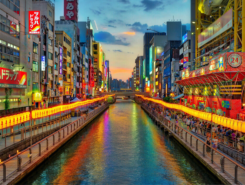 Vibrant night view of Dotonbori Canal in Osaka with neon signs and reflections on the water.