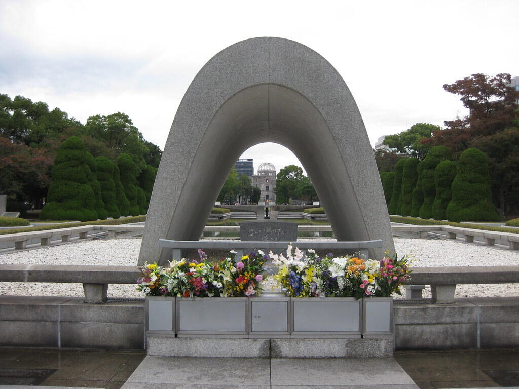 The Memorial Cenotaph at Peace Memorial Park in Hiroshima, with fresh flowers placed at its base.