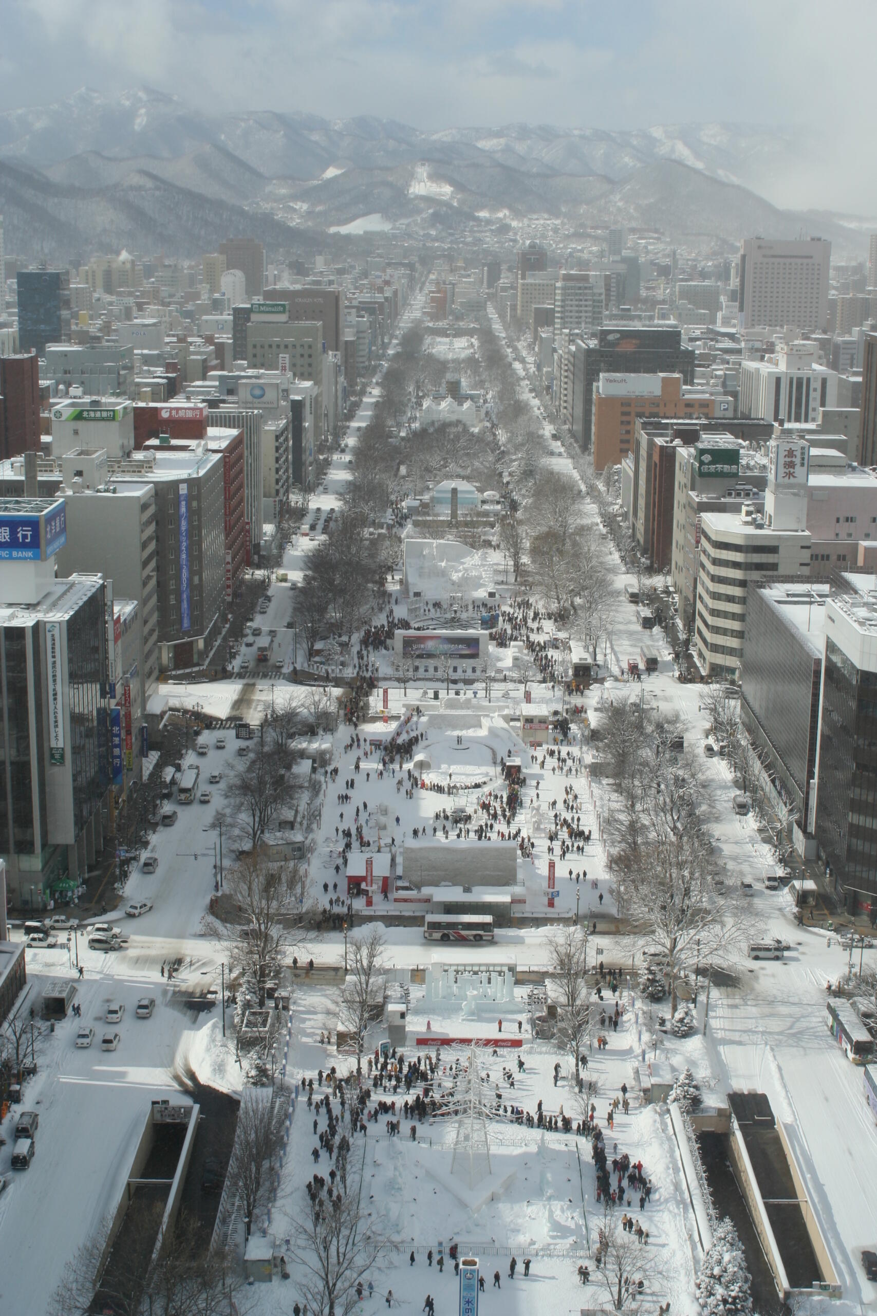 Aerial view of Sapporoâs Odori Park during winter, with snow-covered buildings and festival installations.