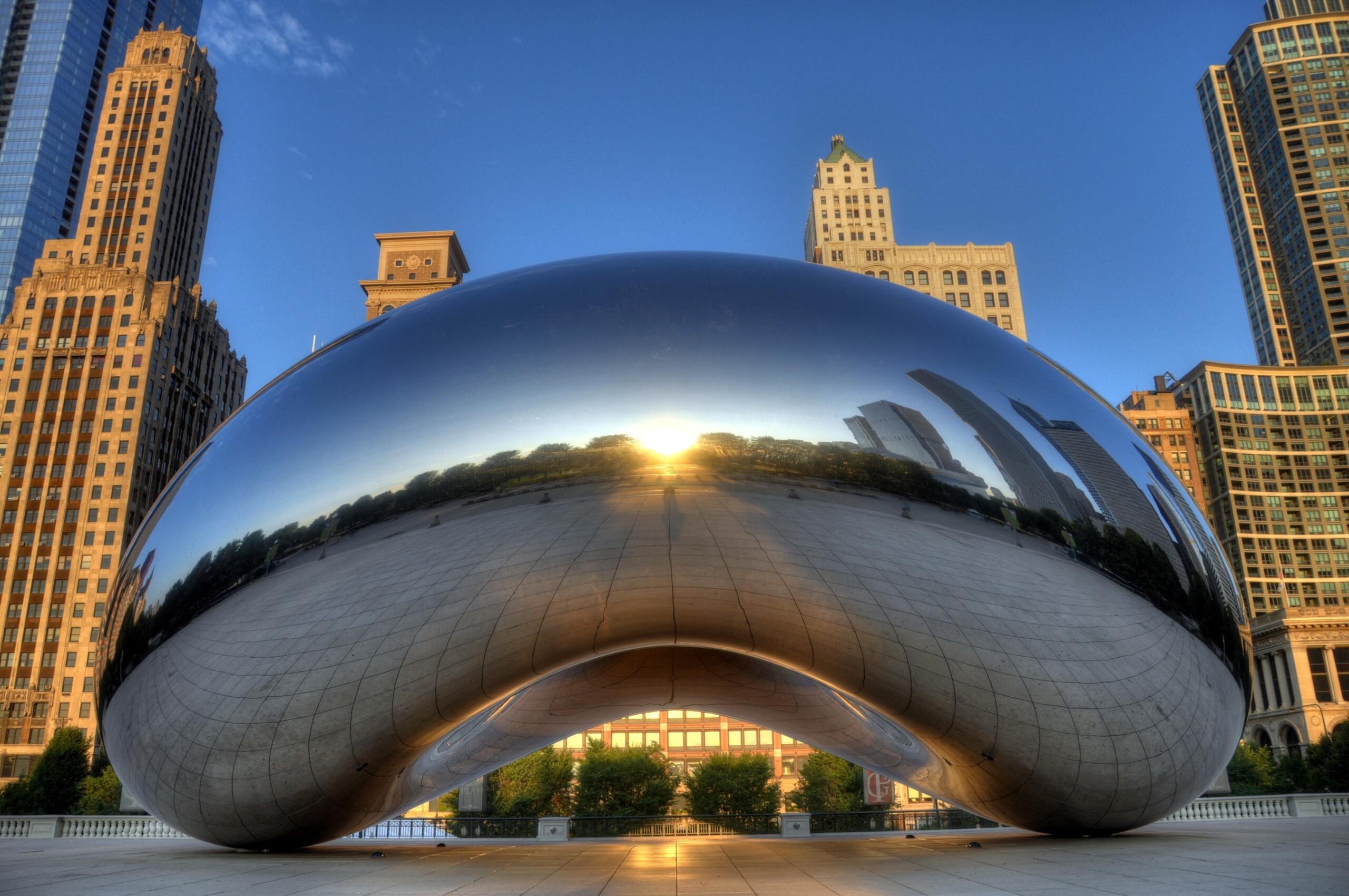 Cloud Gate sculpture reflecting Chicago's skyline and sunrise in Millennium Park.