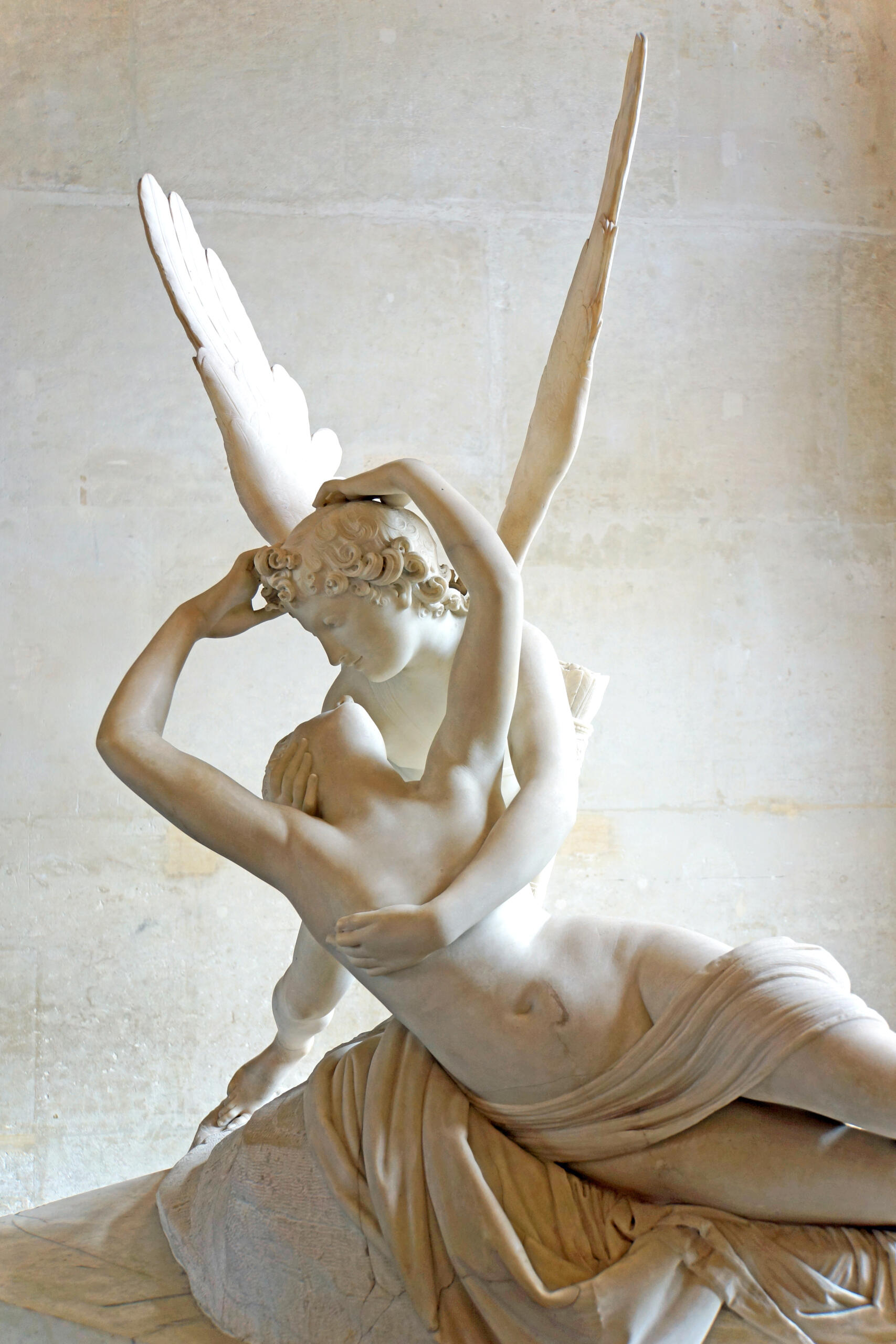 Marble sculpture of Cupid embracing Psyche as she awakens with outstretched wings.