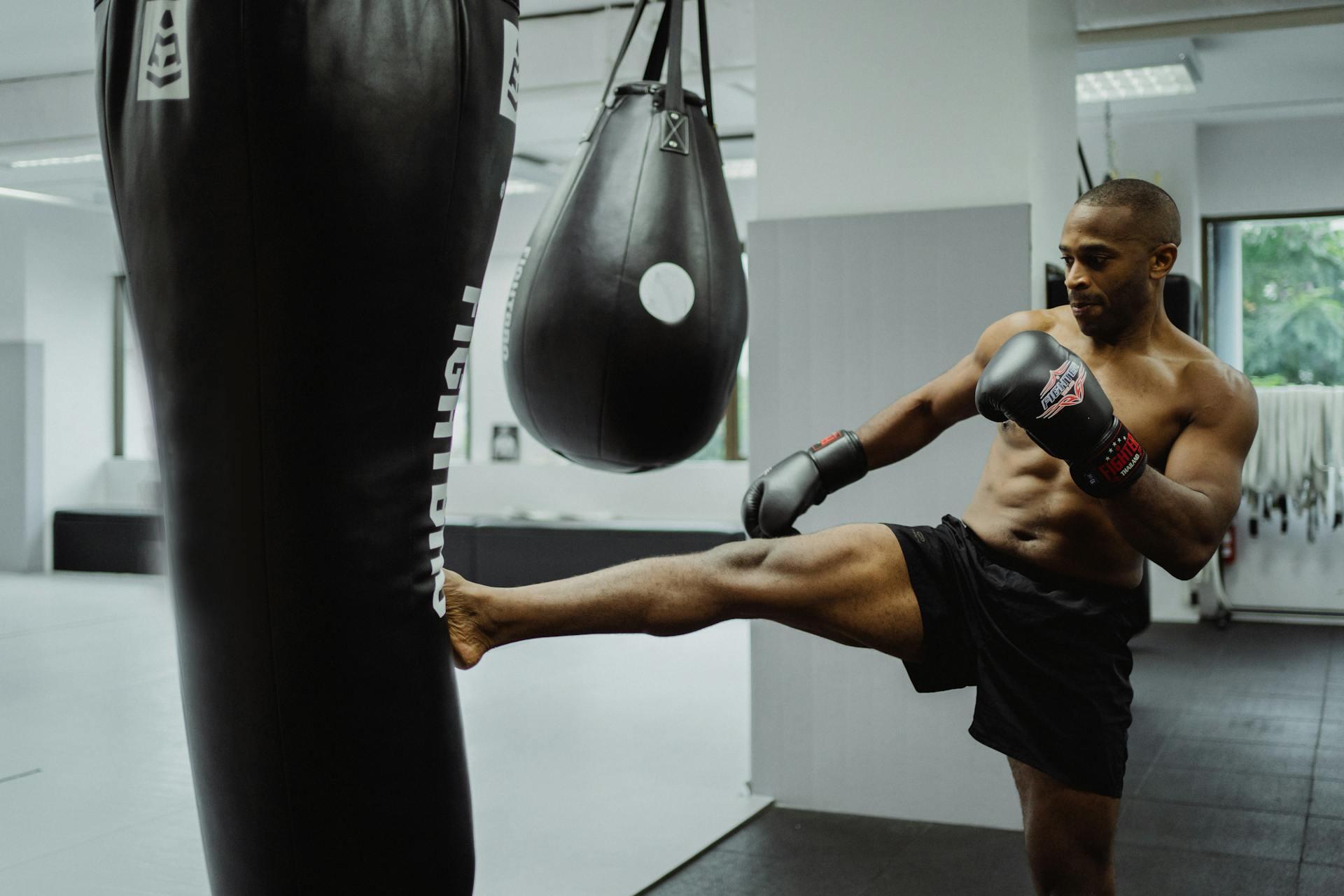 Kickboxer kicking a heavy bag and wearing boxing gloves