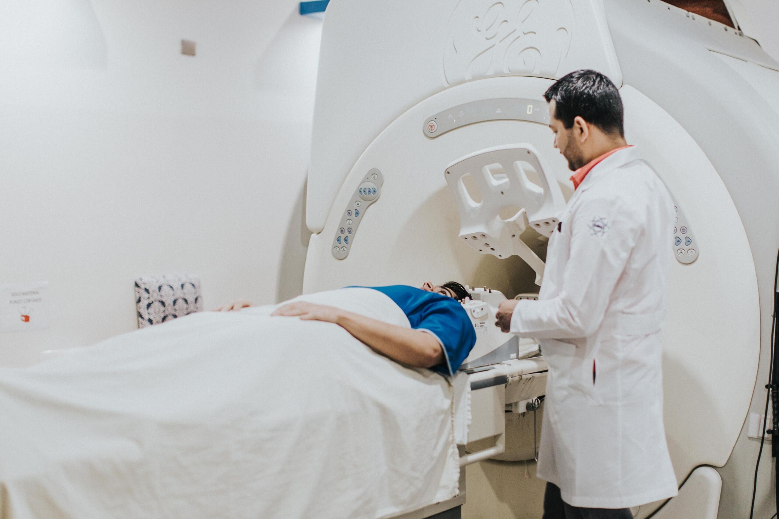 Doctor assisting a man undergoing an MRI scan inside a medical imaging machine.