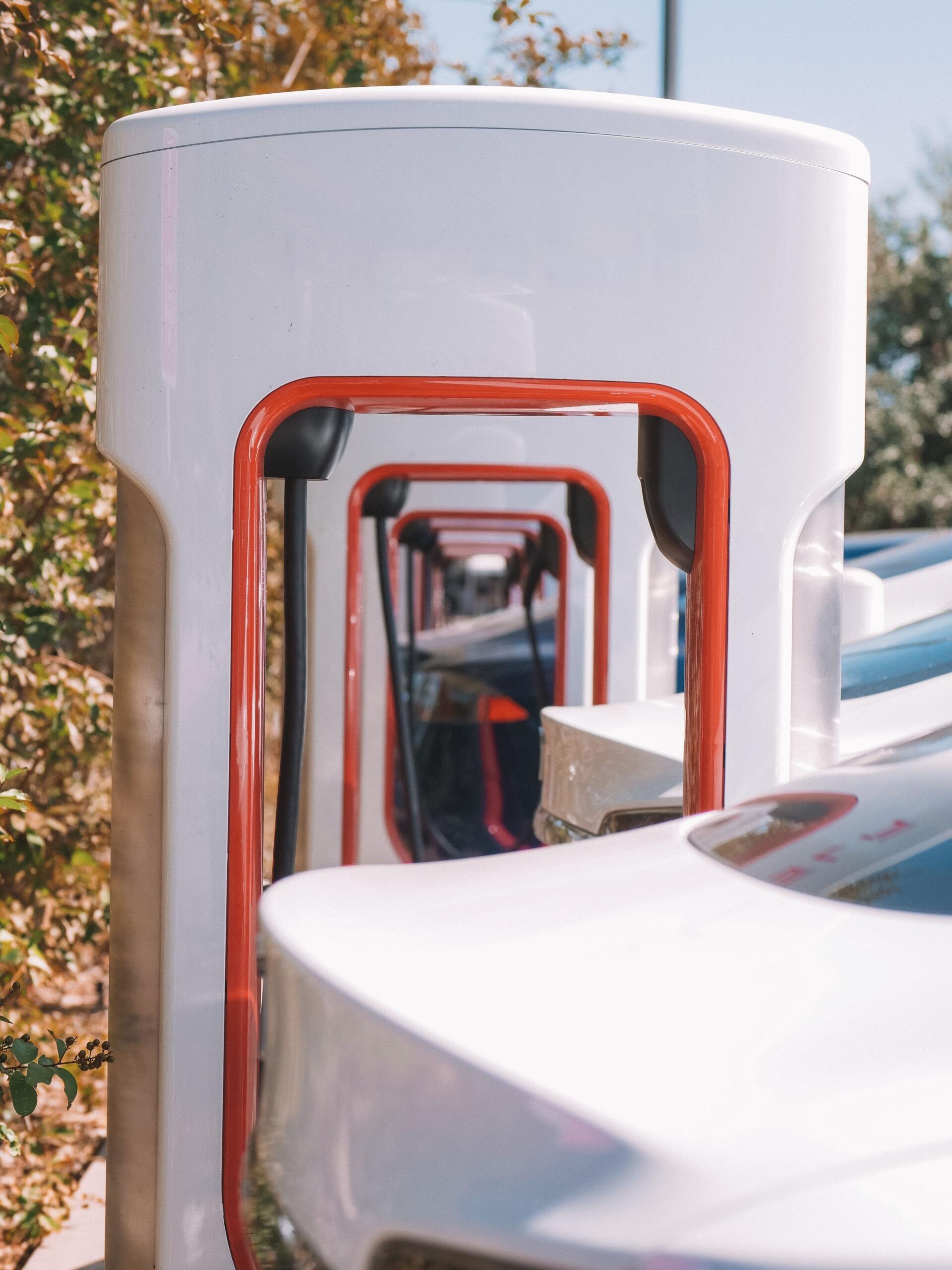 Electric car parked in front of a row of EV charging stations, illustrating technology used to transfer electrical energy to electric vehicles.