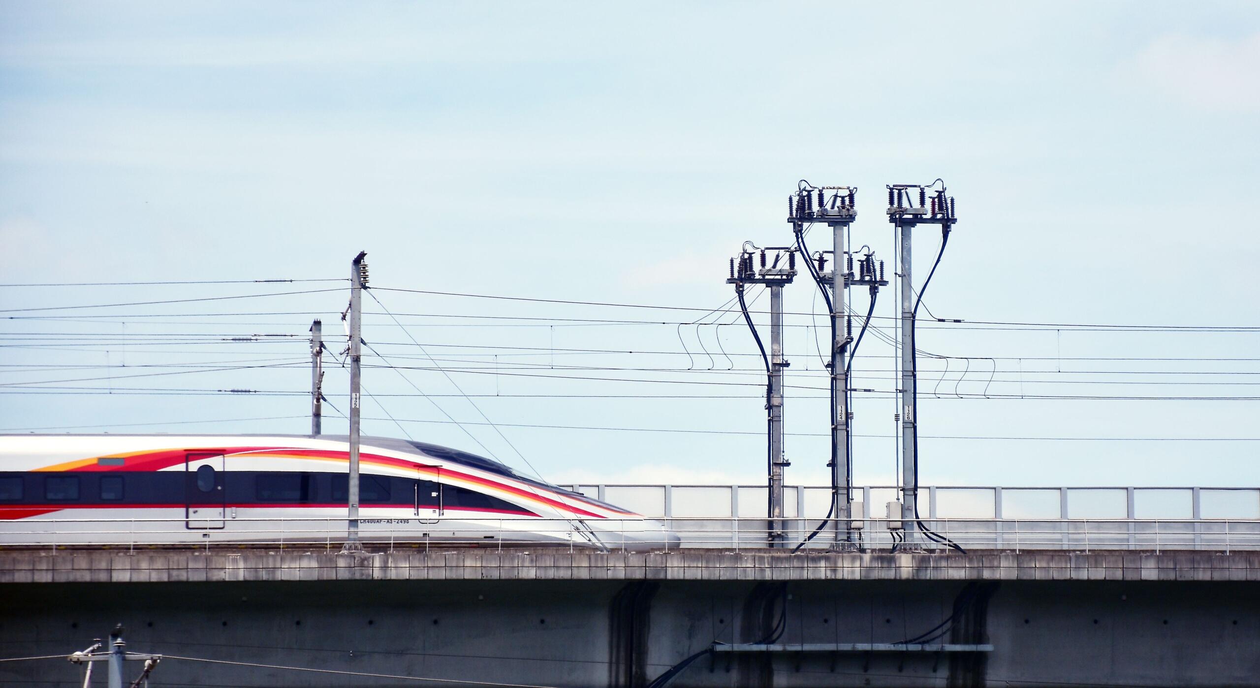 A red and white maglev train travelling along an elevated bridge, demonstrating high-speed transportation powered by magnetic technology.