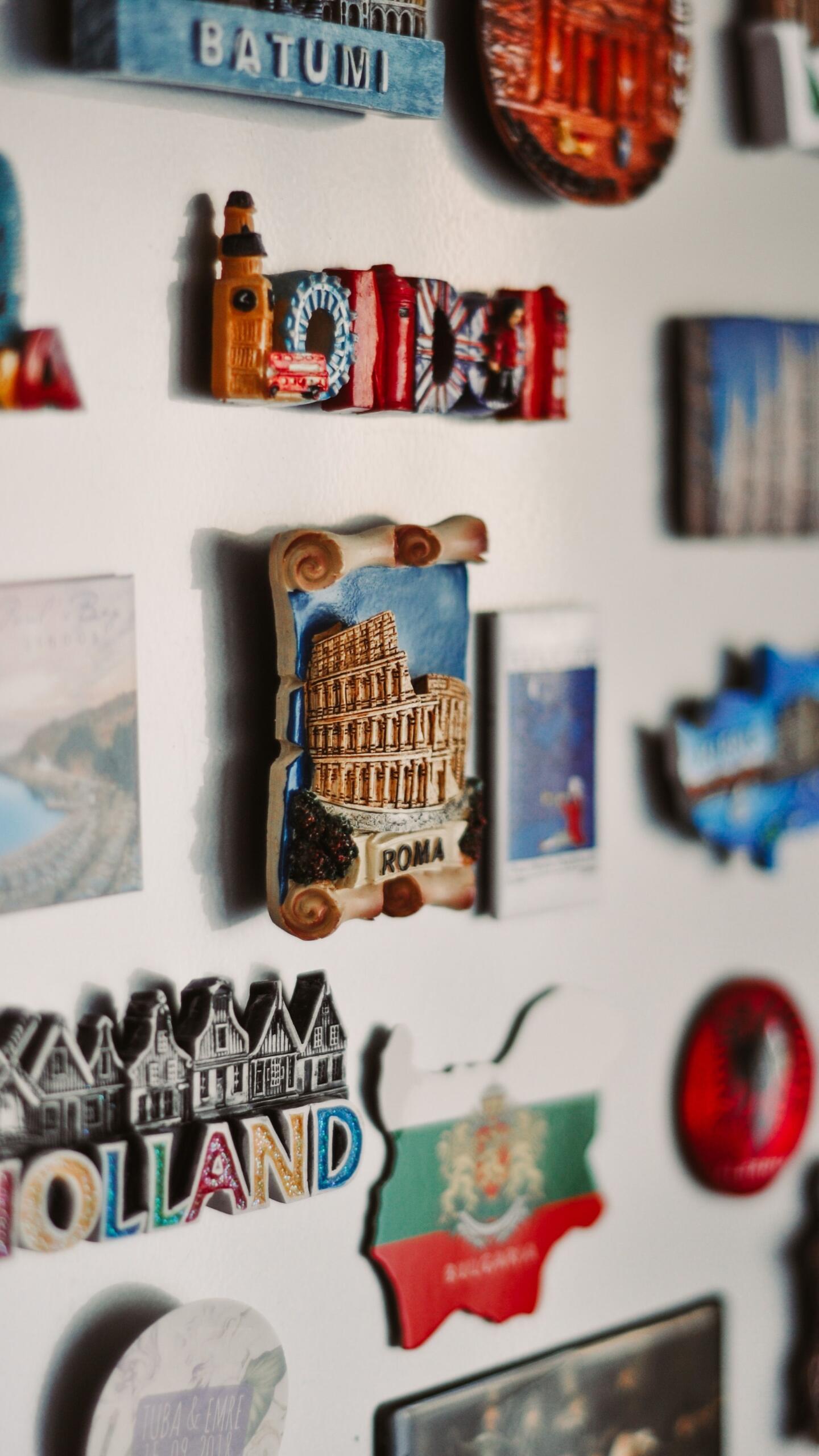 Colourful souvenir refrigerator magnets from different destinations displayed together on a fridge door.