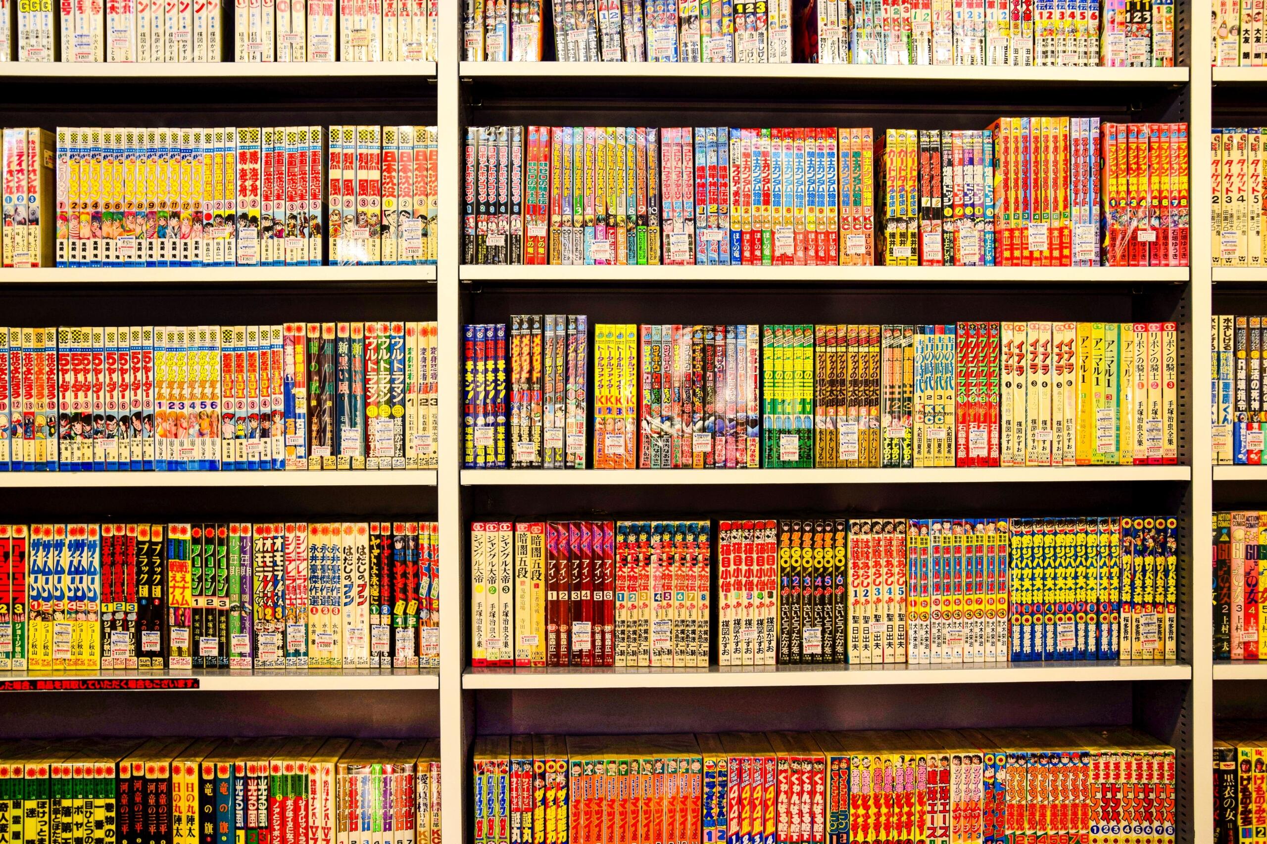A wall filled with neatly arranged manga volumes, their colorful spines creating a vibrant display of Japanese comics. Floor-to-ceiling bookshelves are packed with popular series, showcasing the wide variety of genres and the rich culture of manga in Japan.