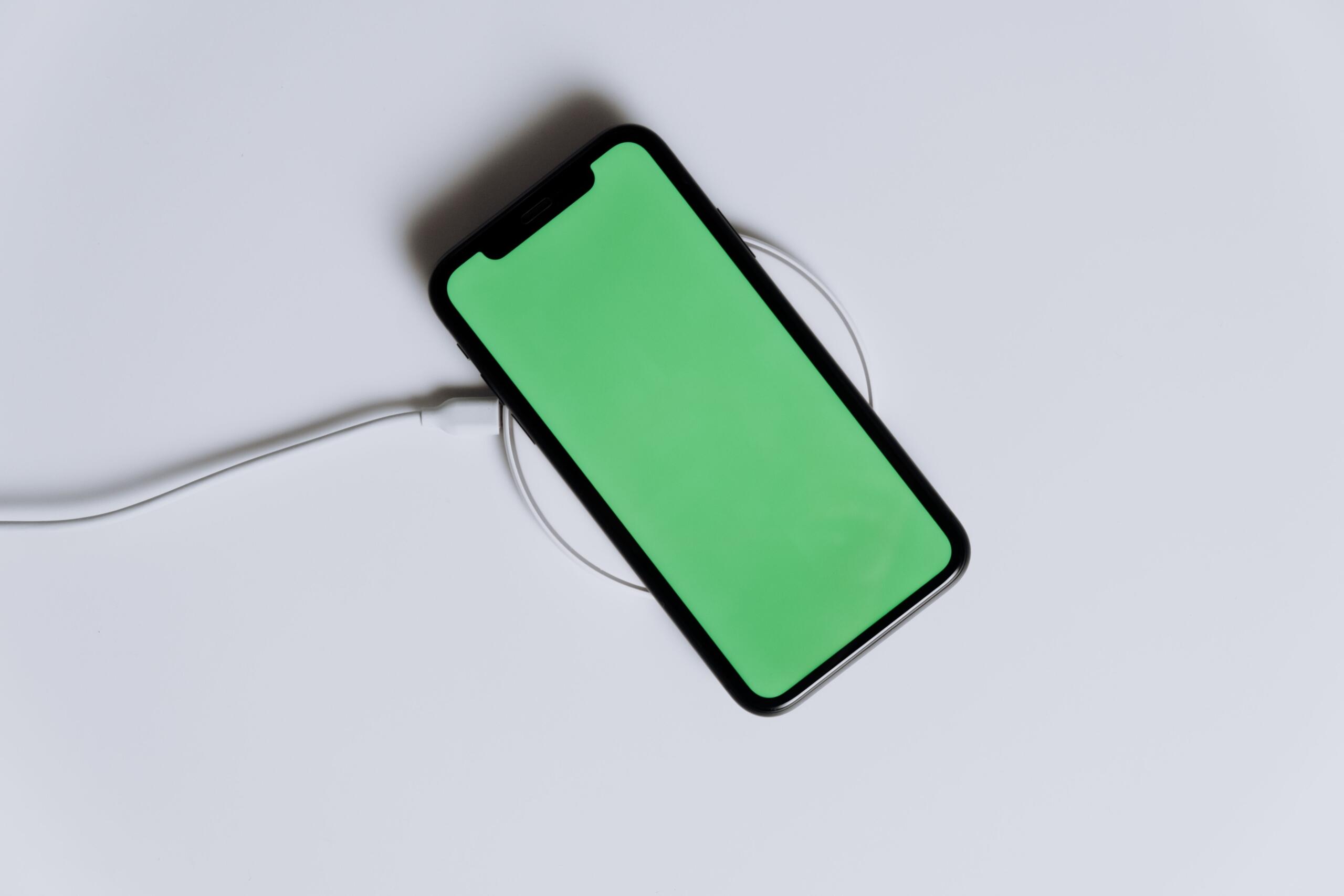 A smartphone rests on a wireless charging pad, receiving power through electromagnetic induction without a wired connection.