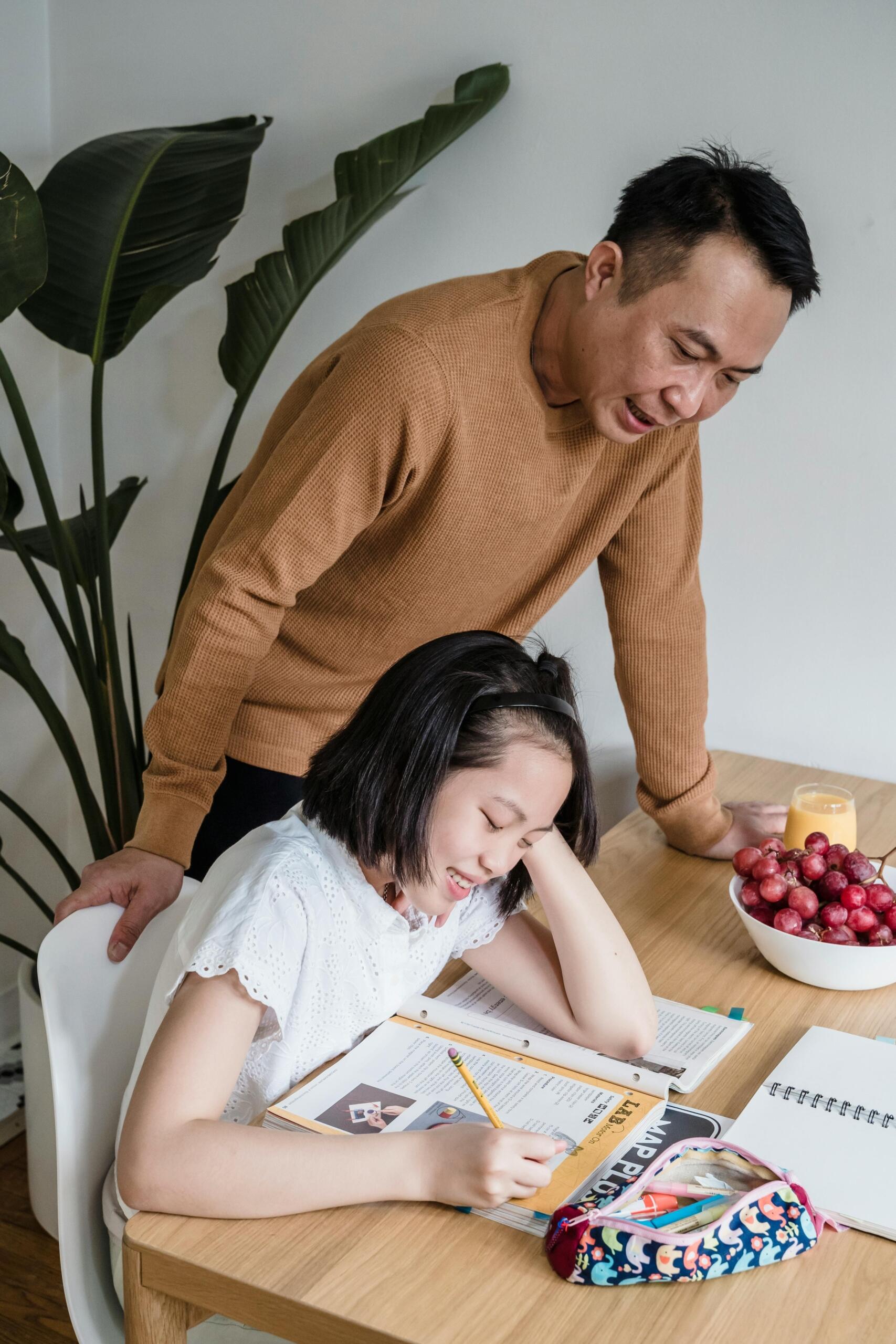a man helps his daughter with her homework.
