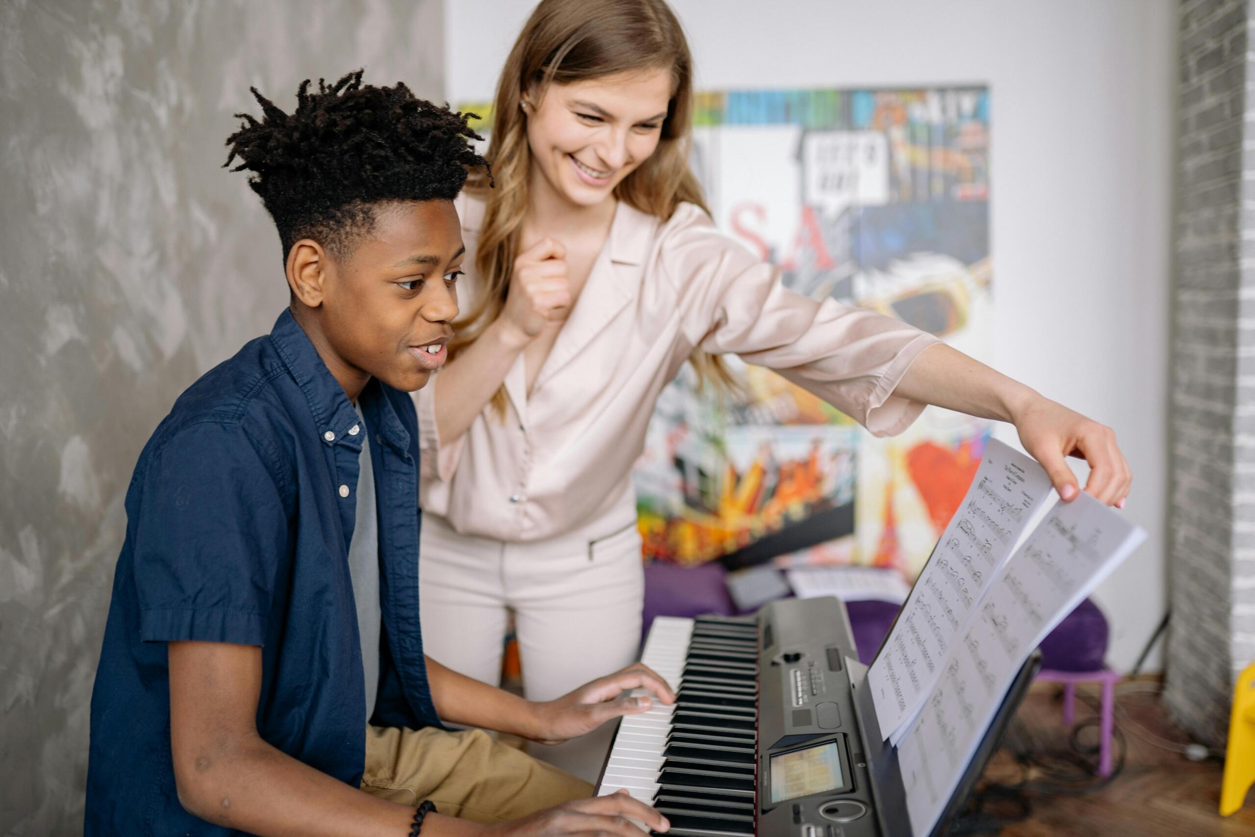 a teenager learns piano from a teacher.