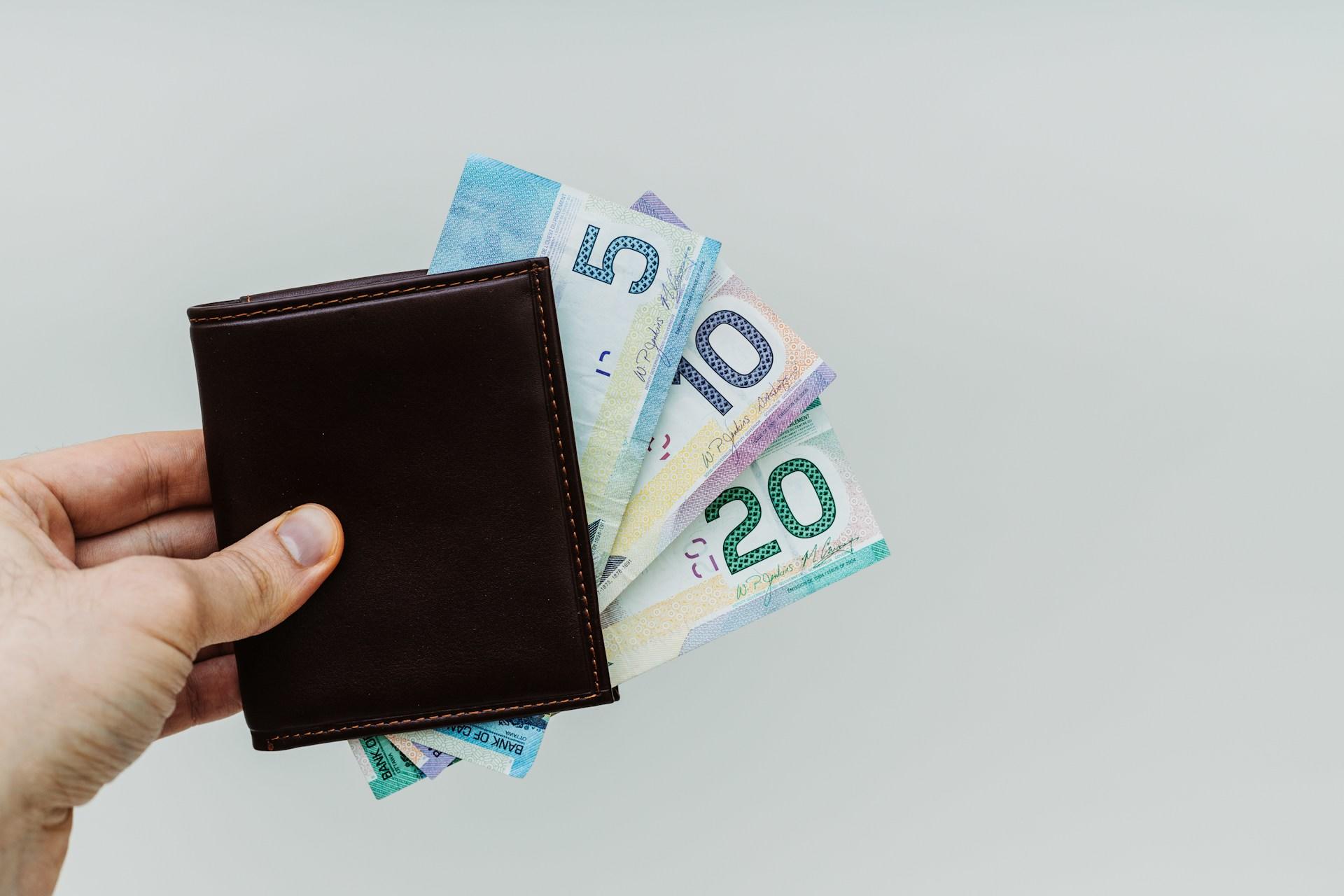 A wallet with a spread of Canadian bills (a $5 bill, $10 bill and $20 bill).