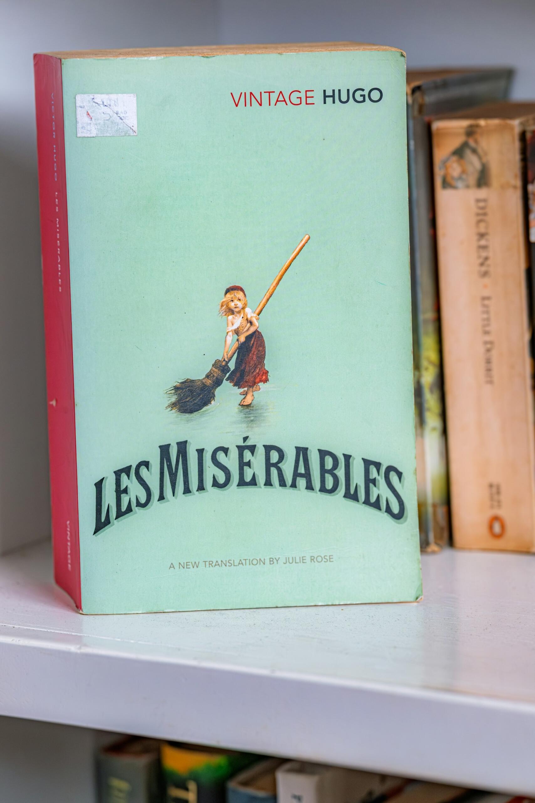 A vintage cover of Les Misérables by Victor Hugo, featuring a drawing of a young girl with a broom.