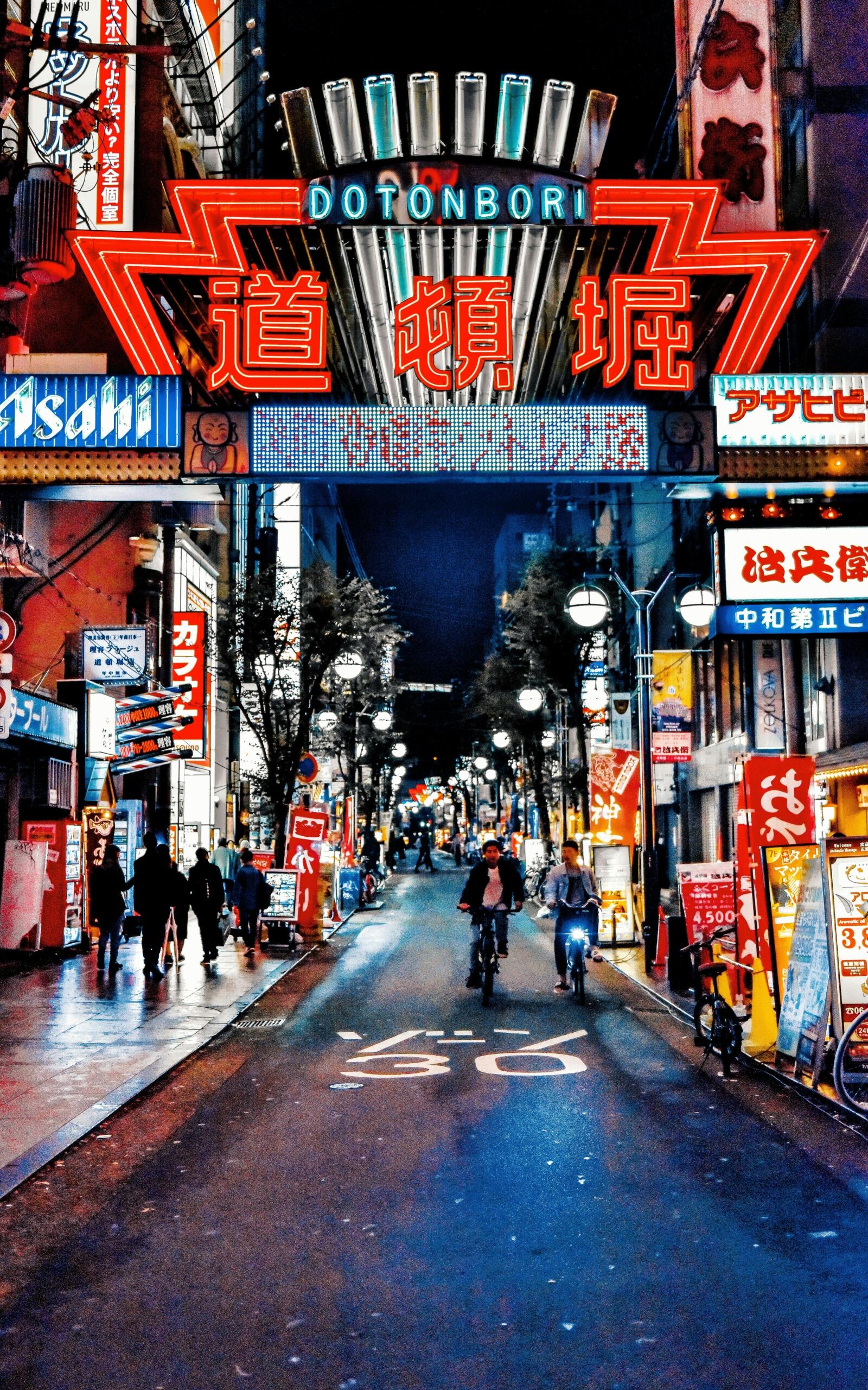Dotonbori, Osaka, glowing with colorful neon signs, giant billboards, and people enjoying food and nightlife.