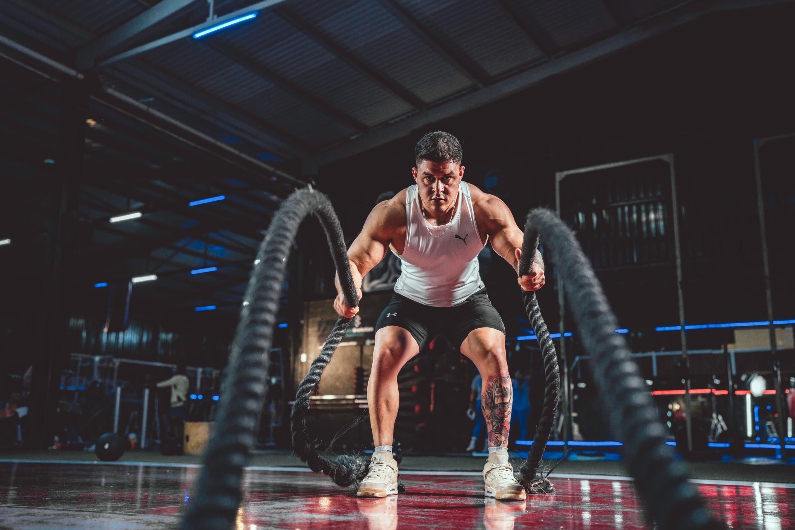 A man trains with battle ropes in a gym, building strength and endurance during a high-intensity workout.