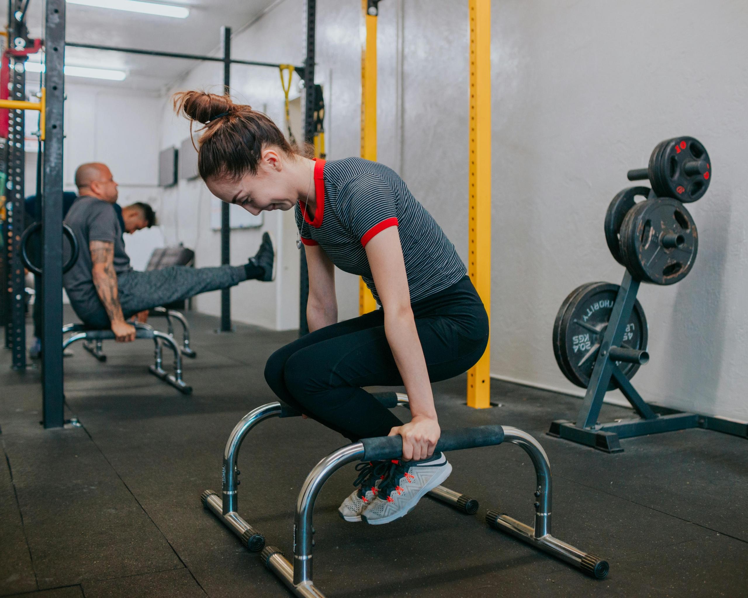 A girl practicing an L sit on parallette bars