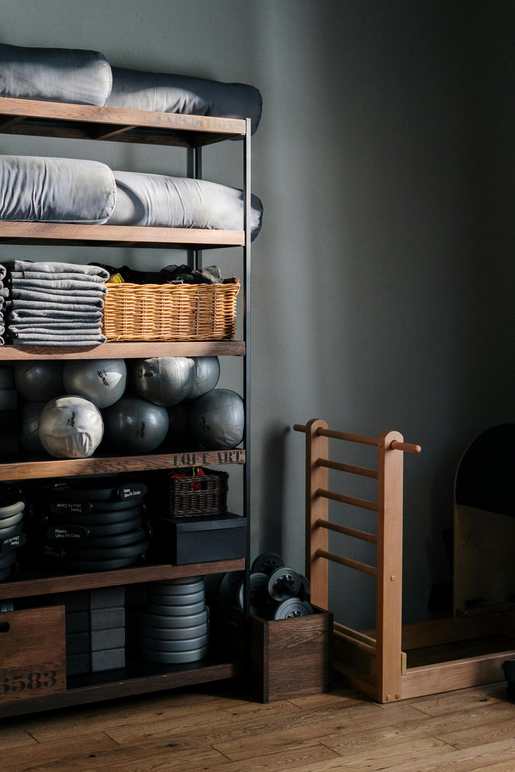 A shelf with gym equipment on it such as towels, medicine balls and plates.