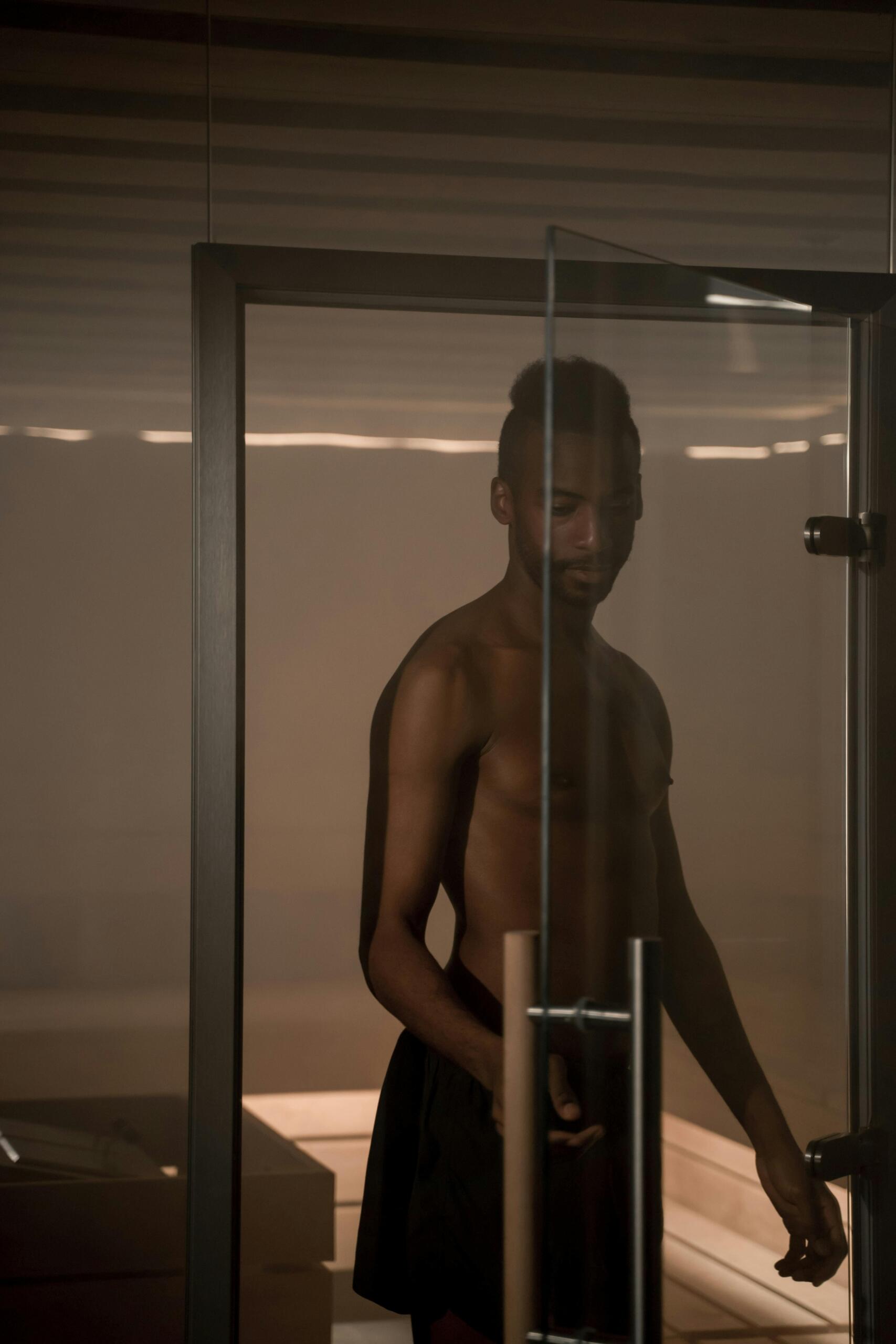 A man wrapped in a towel stepping into a dimly lit steam room. Source: Ron Lach.