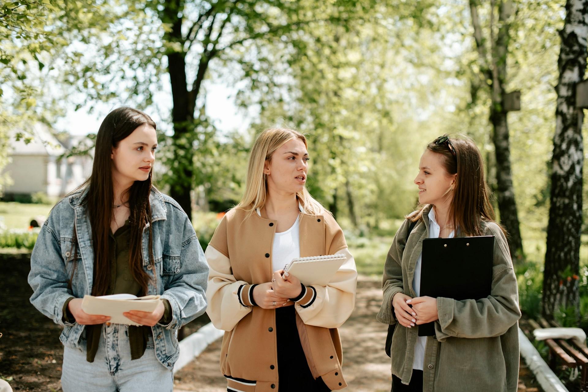 3 female students discussing stats while walking to class. 