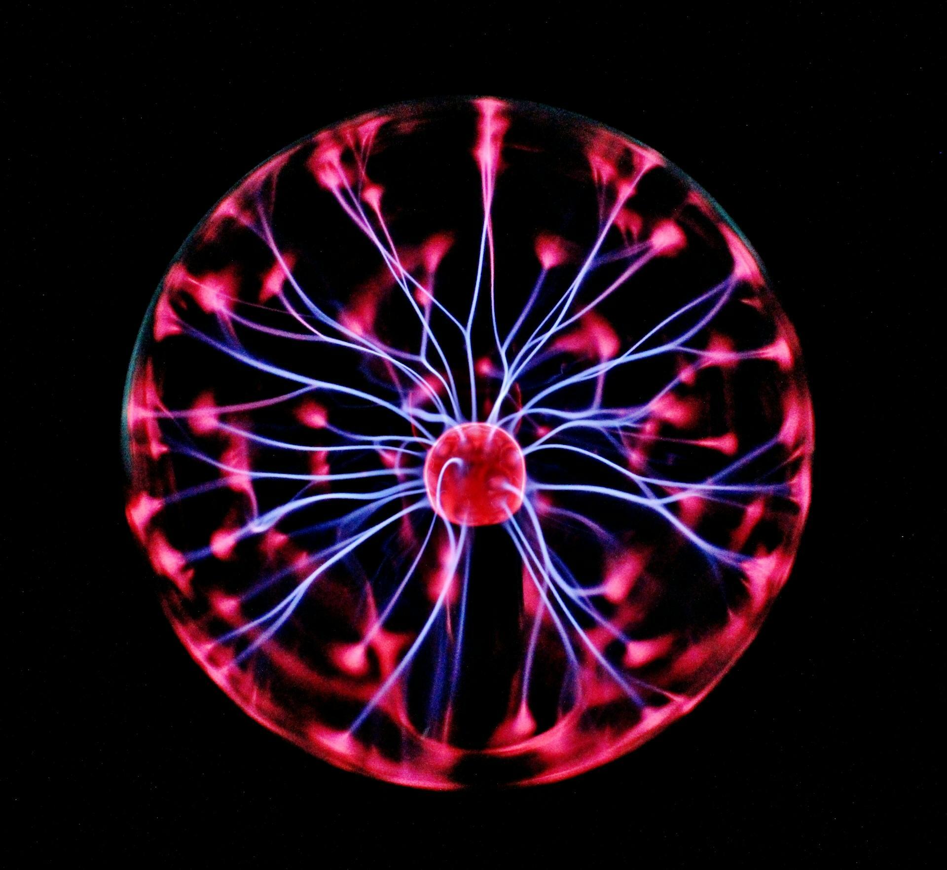 A glowing plasma ball emits streams of purple and red light, creating a mesmerizing pattern against a dark background.