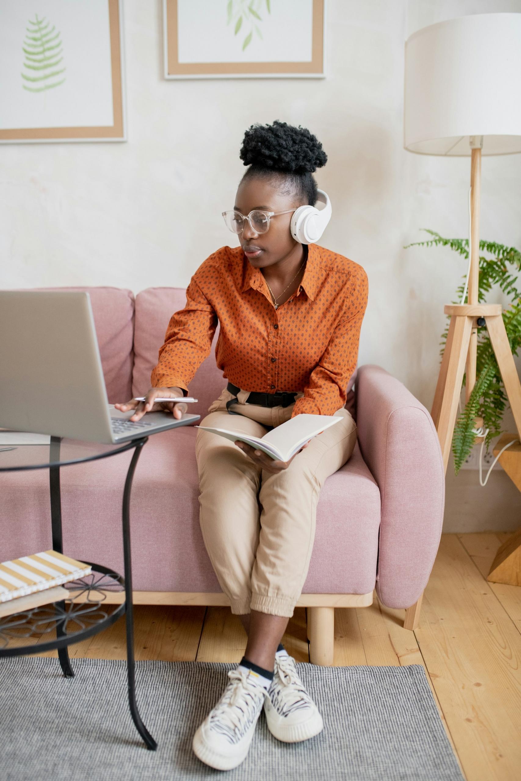 A women sitting on the couch studying stats with her laptop.