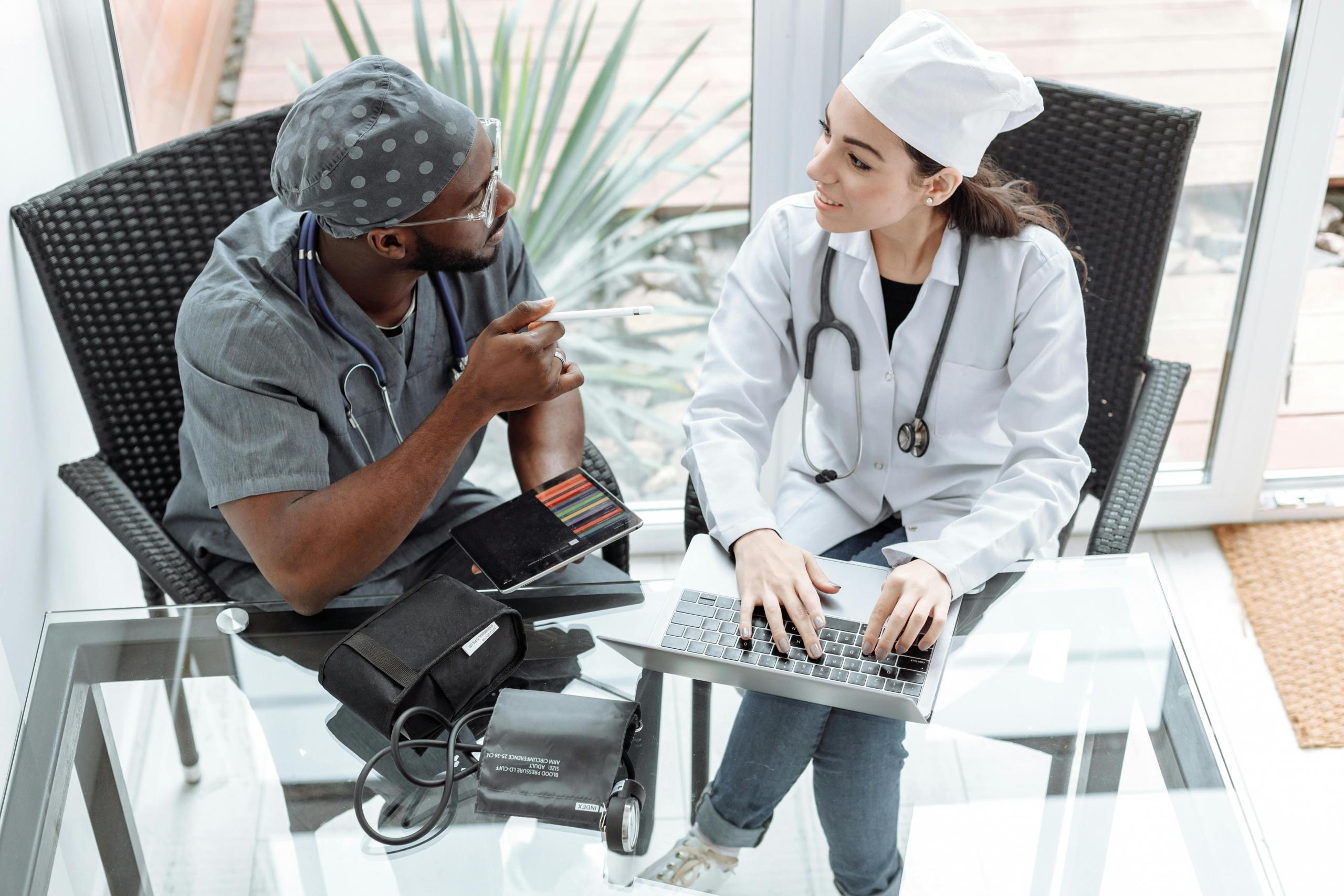 A doctor and surgeon are sitting together at a desk discussing a patient.