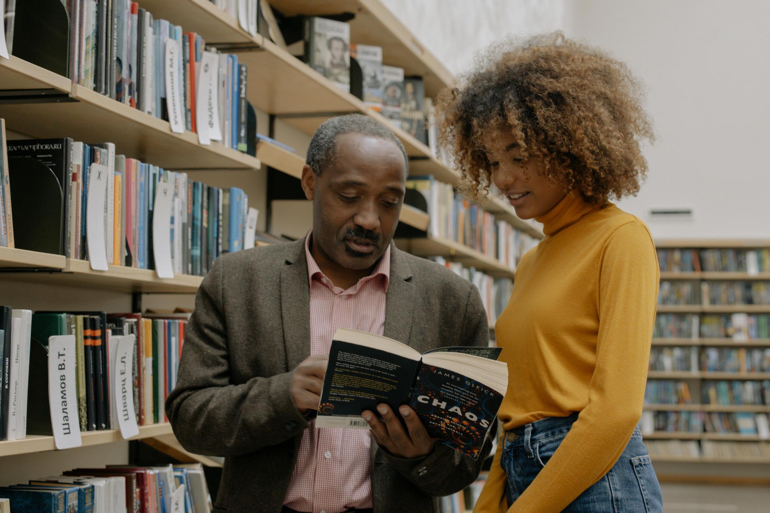 a professor looks at a book with a student.