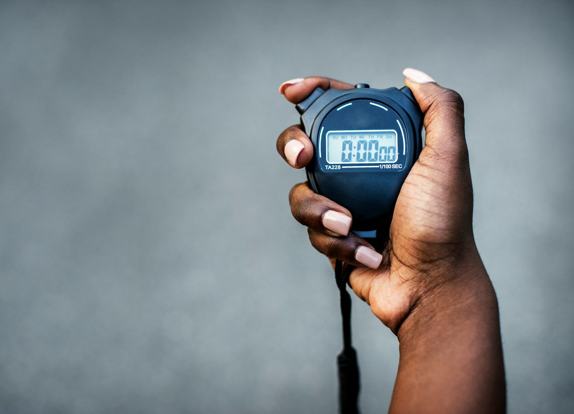 Hand holding a stopwatch showing zero seconds on the display.