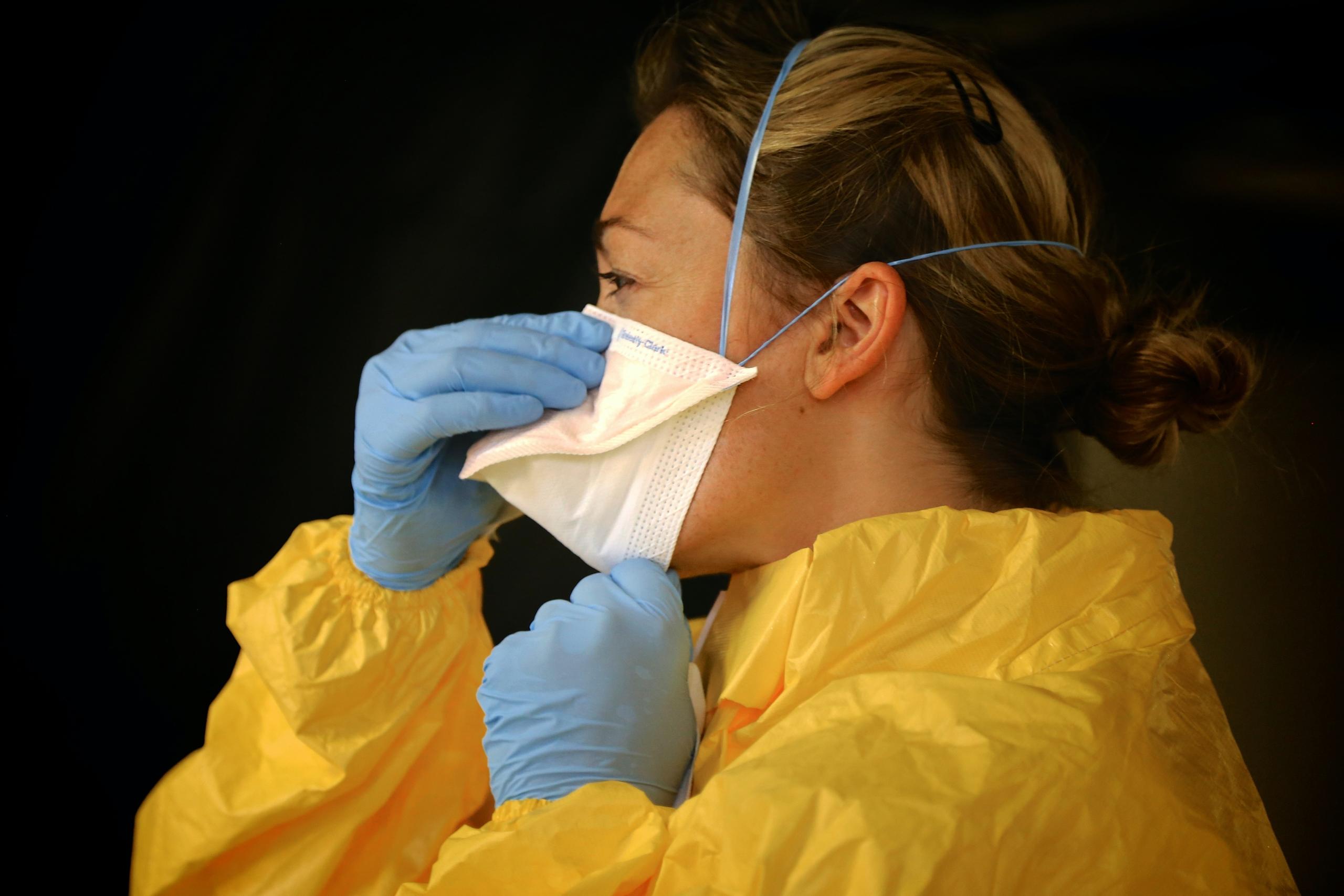 A nurse adjusts her mask.