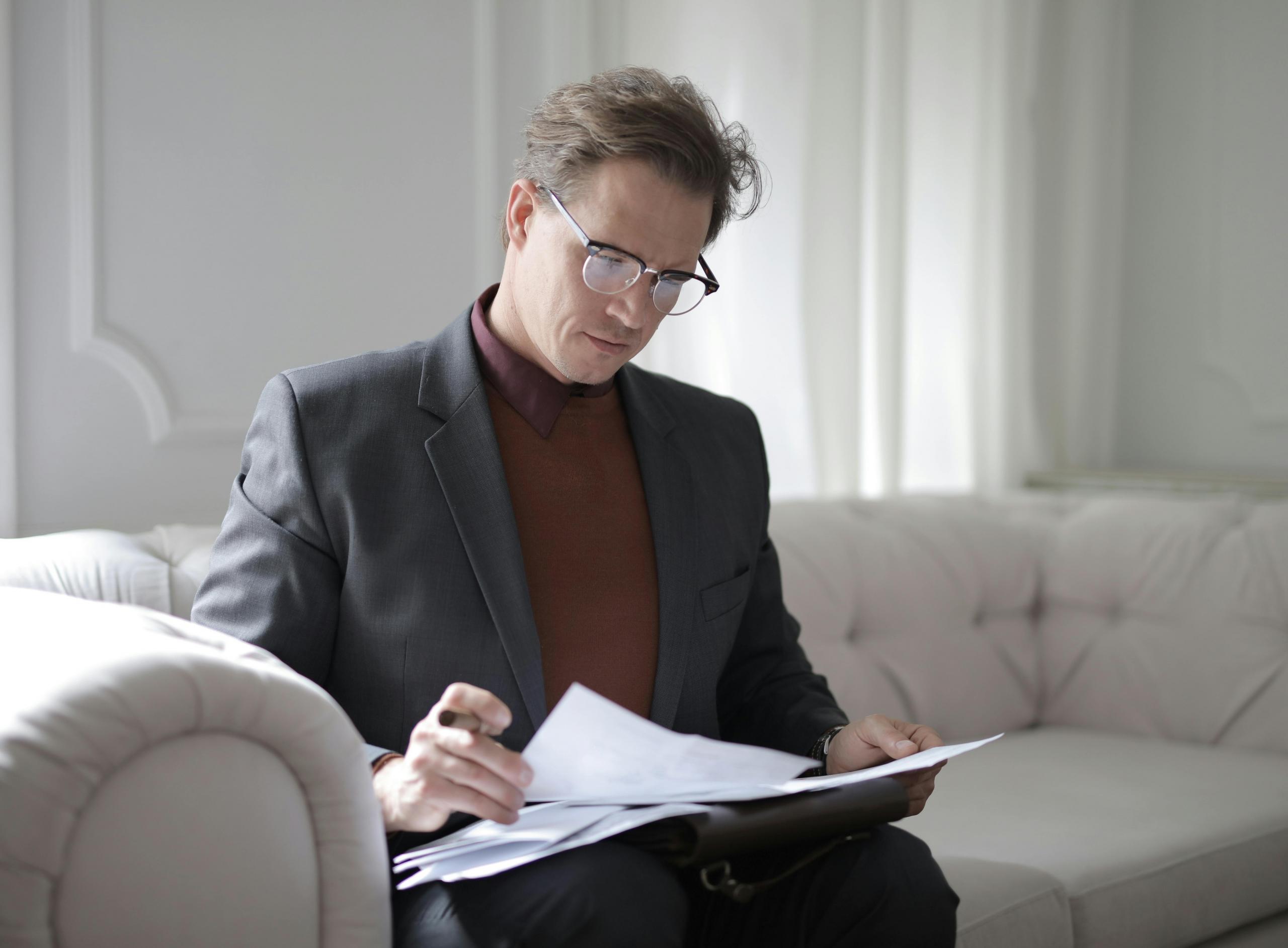 A family lawyer sitting on the couch reviewing a file.