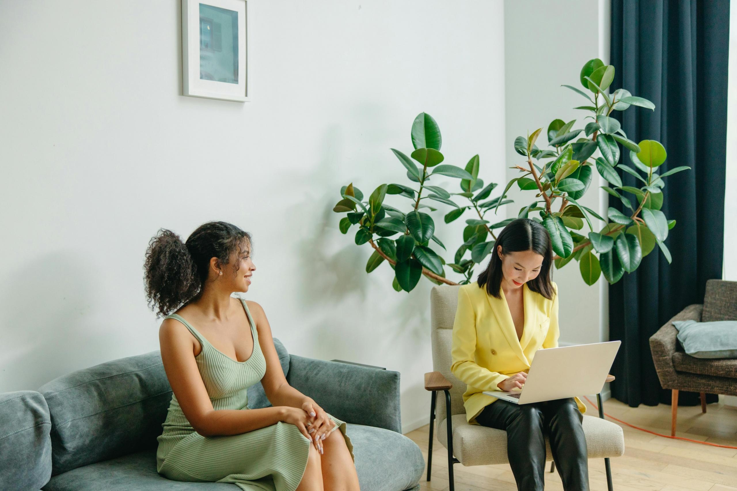 A nutritionist is sitting down with her client taking notes on the laptop.