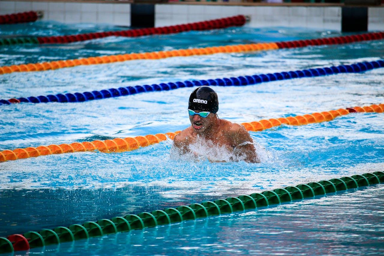 A male swimmer in a lane pool is getting feedback from the coach.