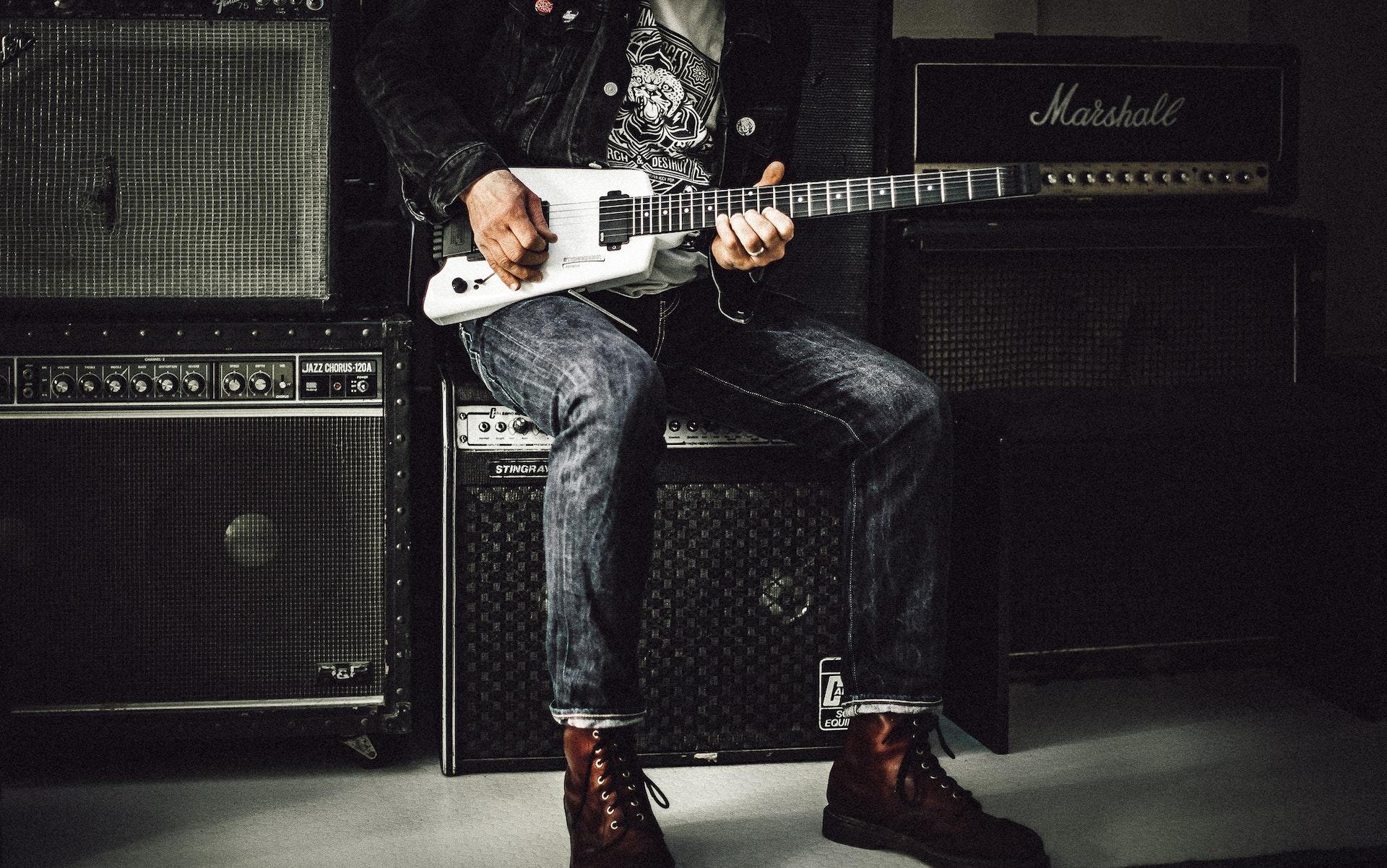 Guitar player sits on amp