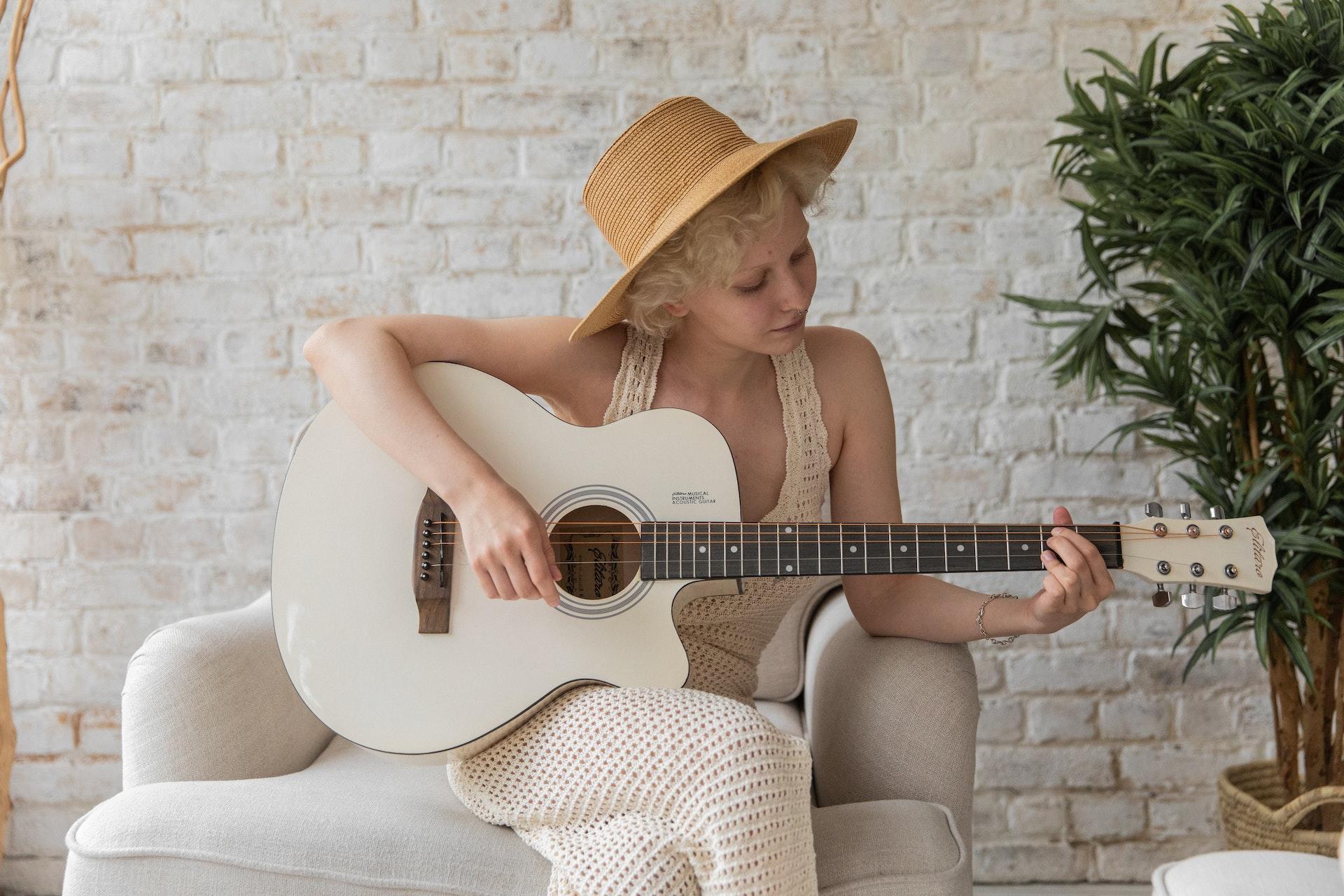 women plays guitar on couch
