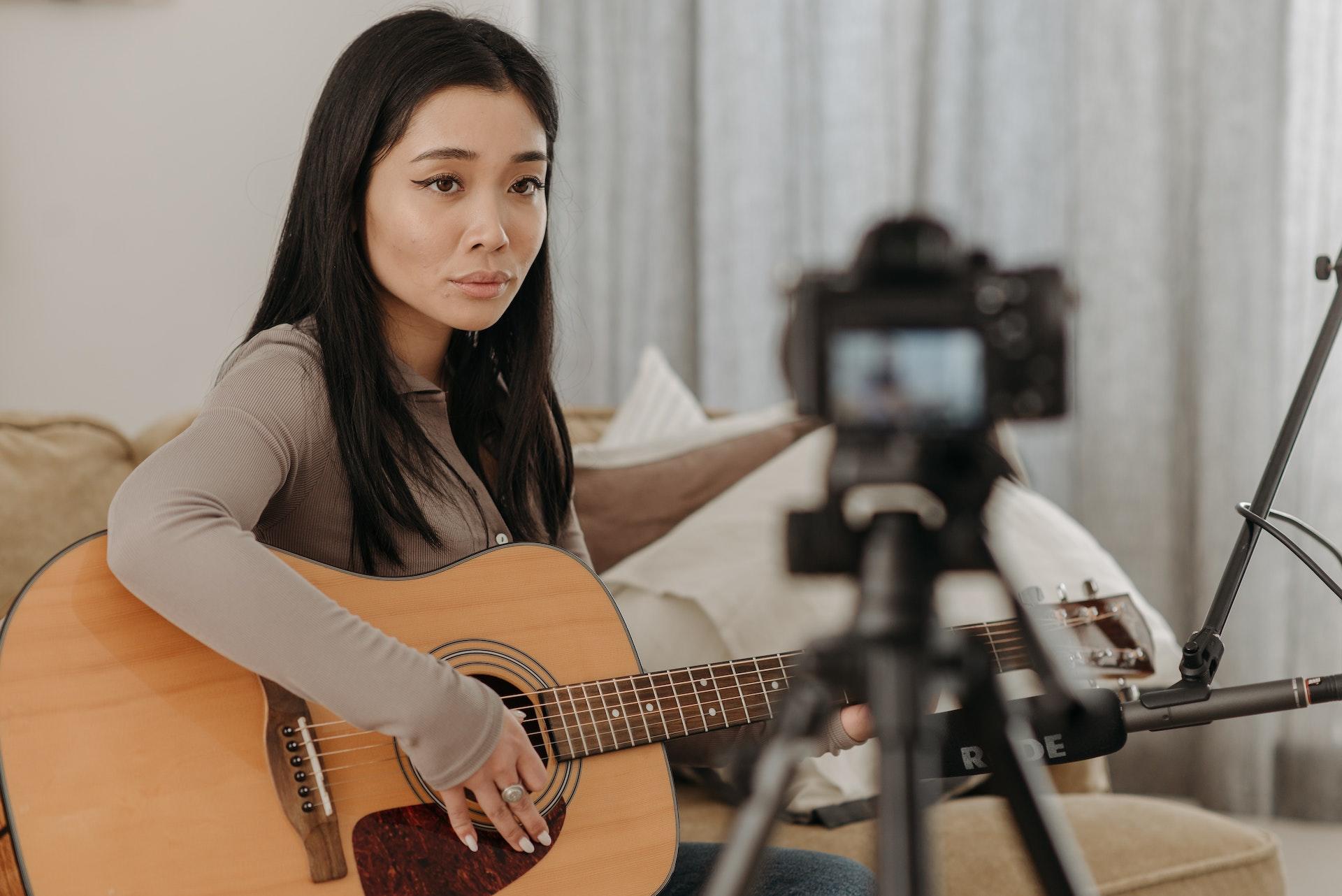 Woman plays guitar on camera