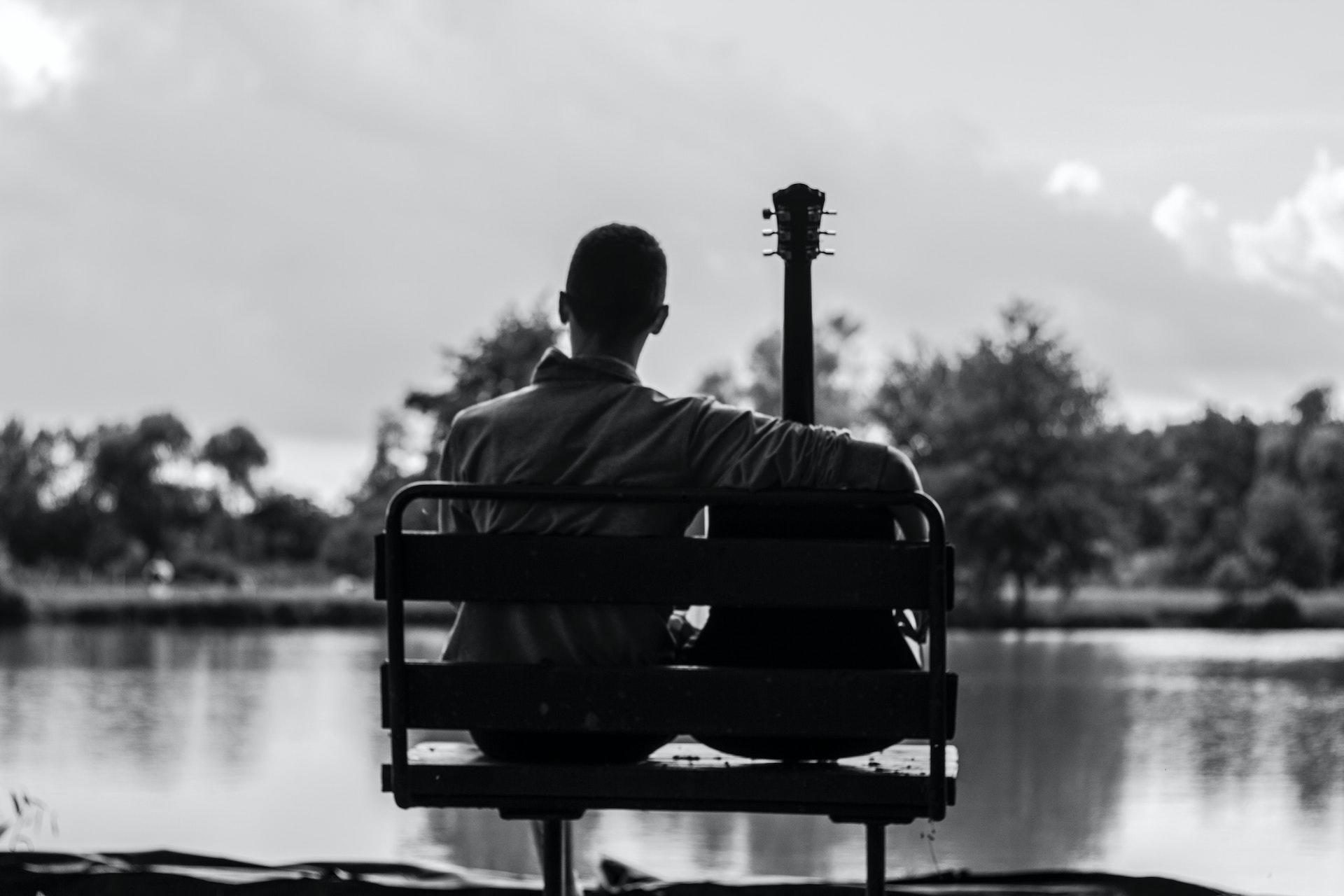 Man sitting with guitar on bench