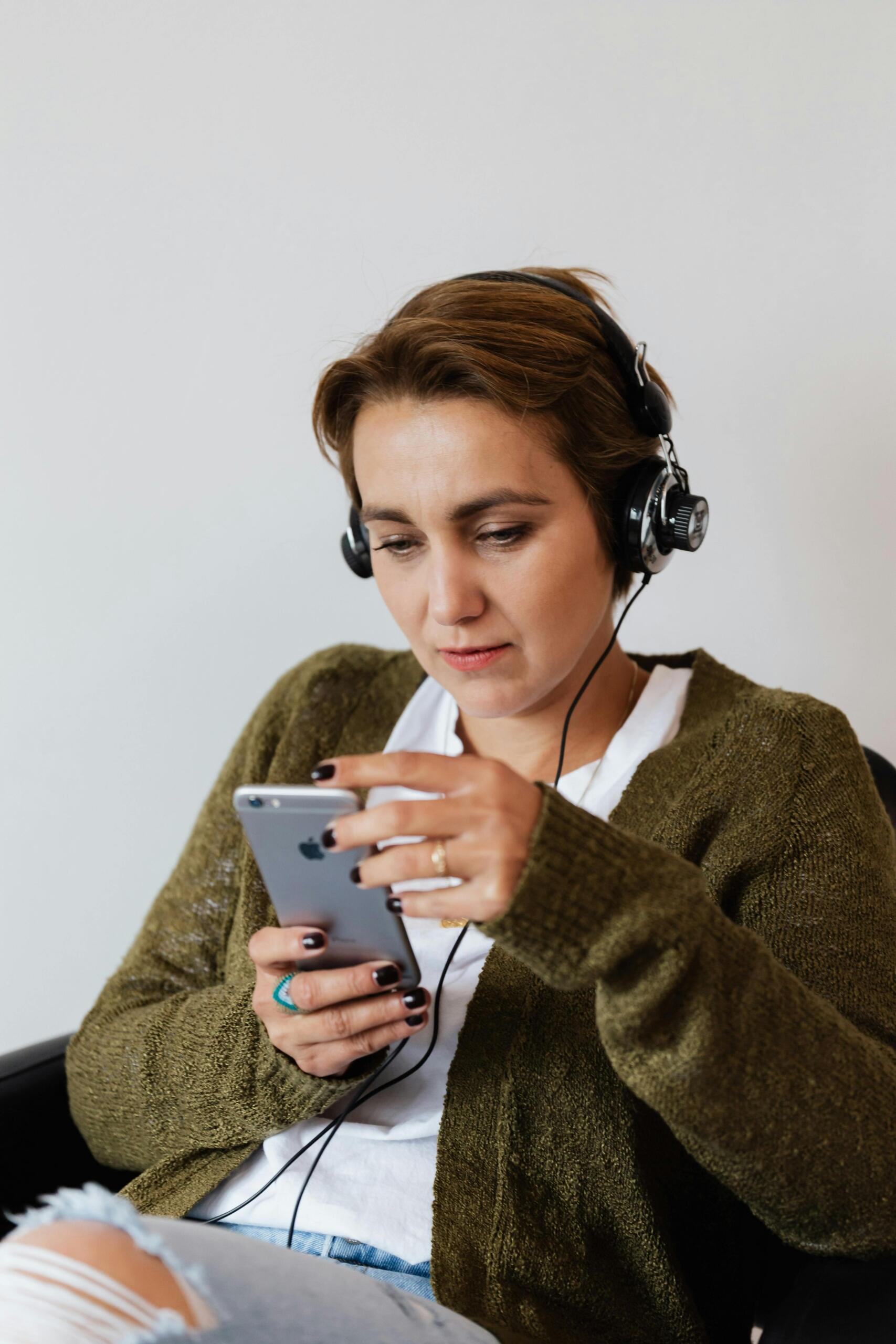 a woman with headphones looks at her iphone. Source: Karola G.
