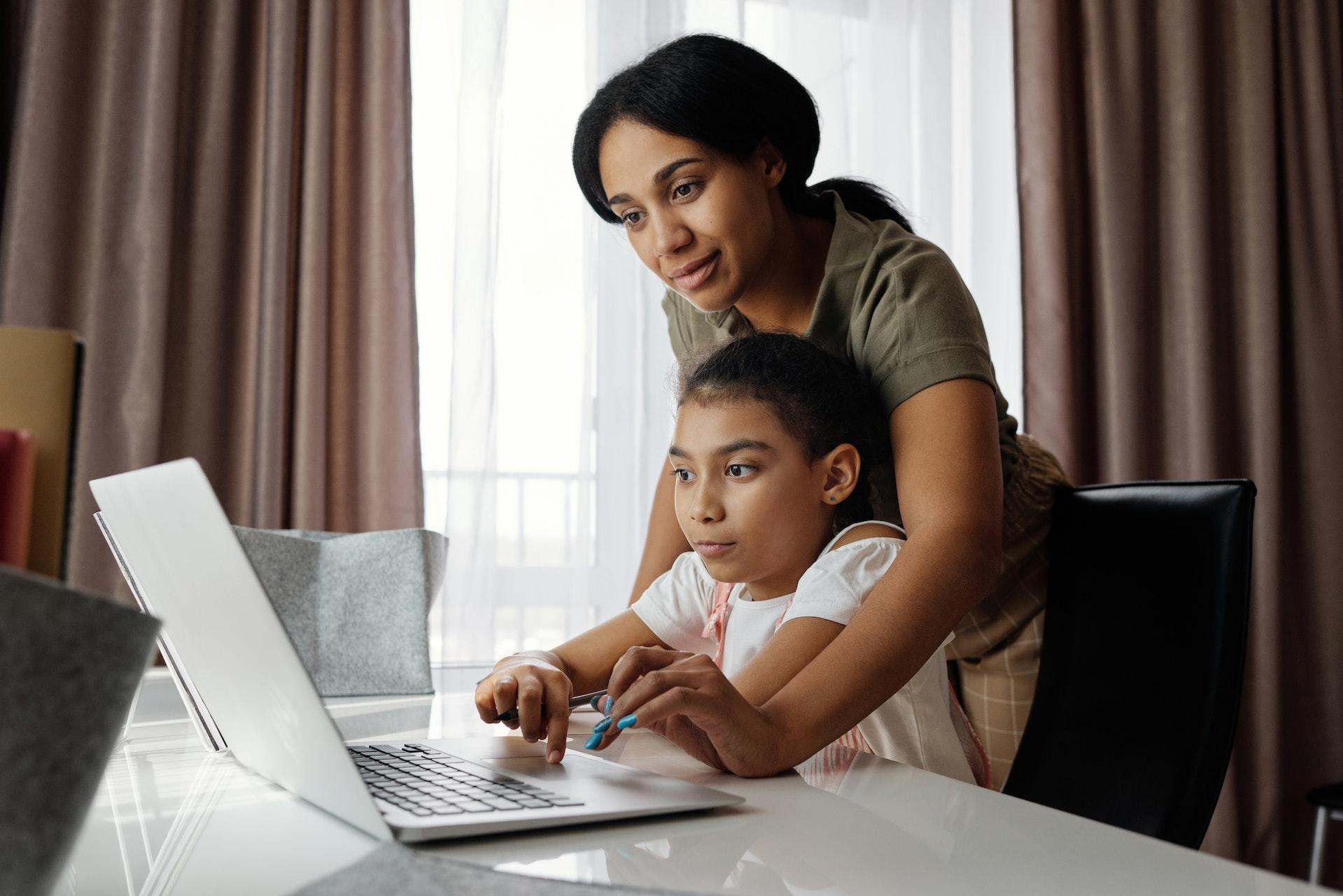mother helping child learn computer skills