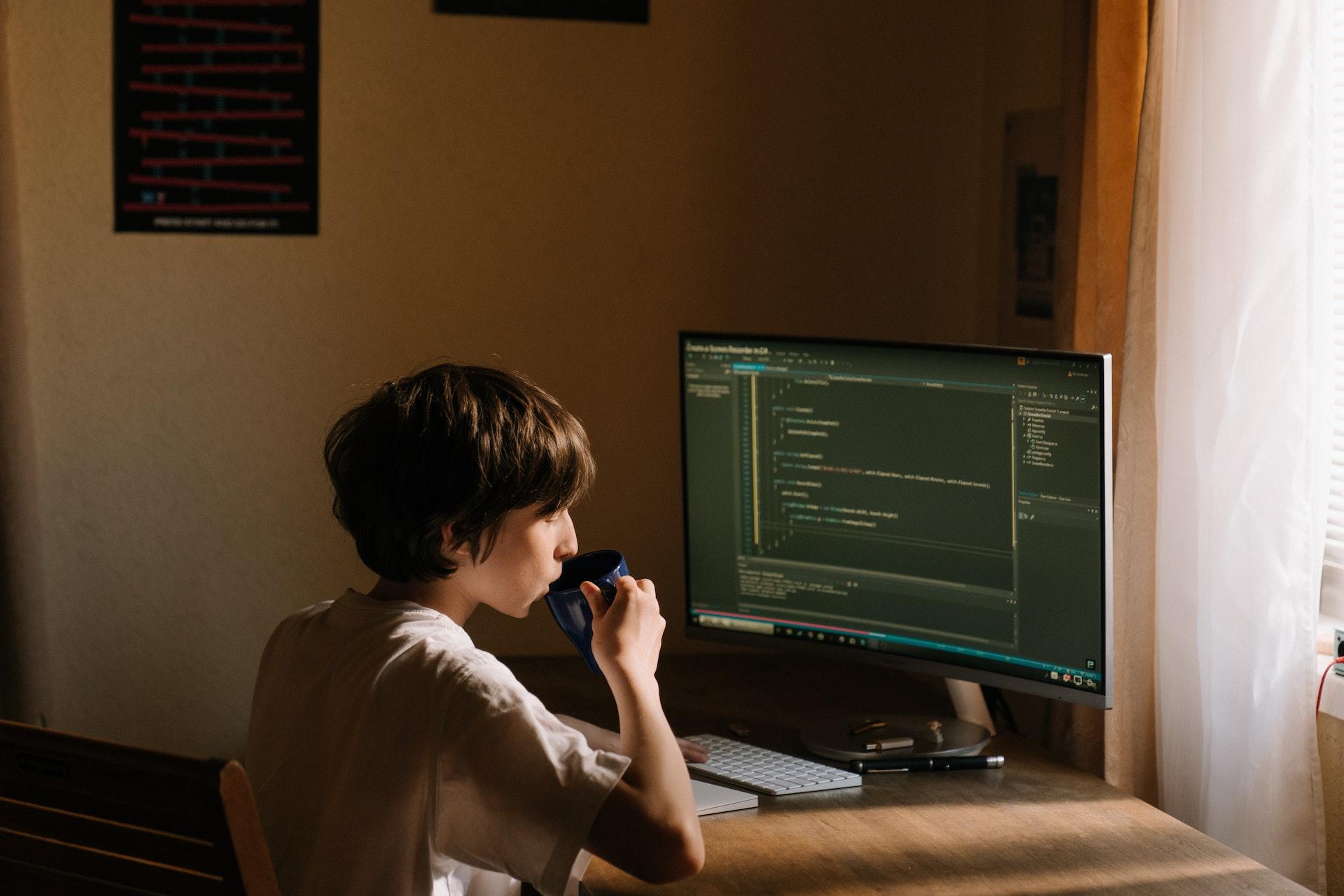 Young boy drinking coffee and coding
