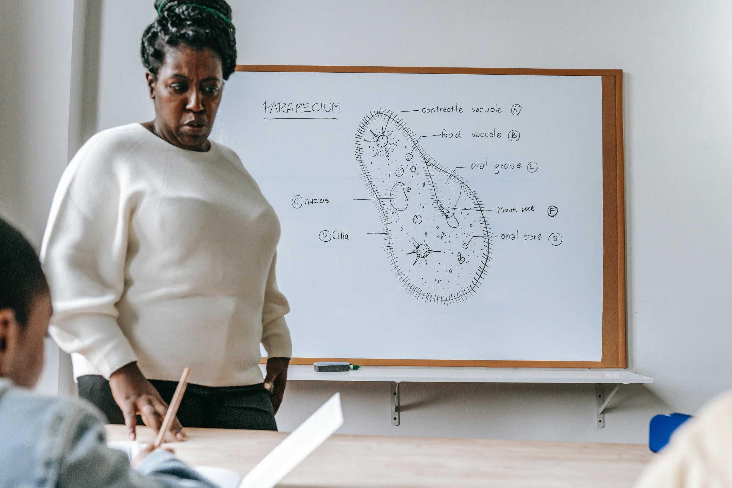 A science teacher stands in front of a cell diagram.