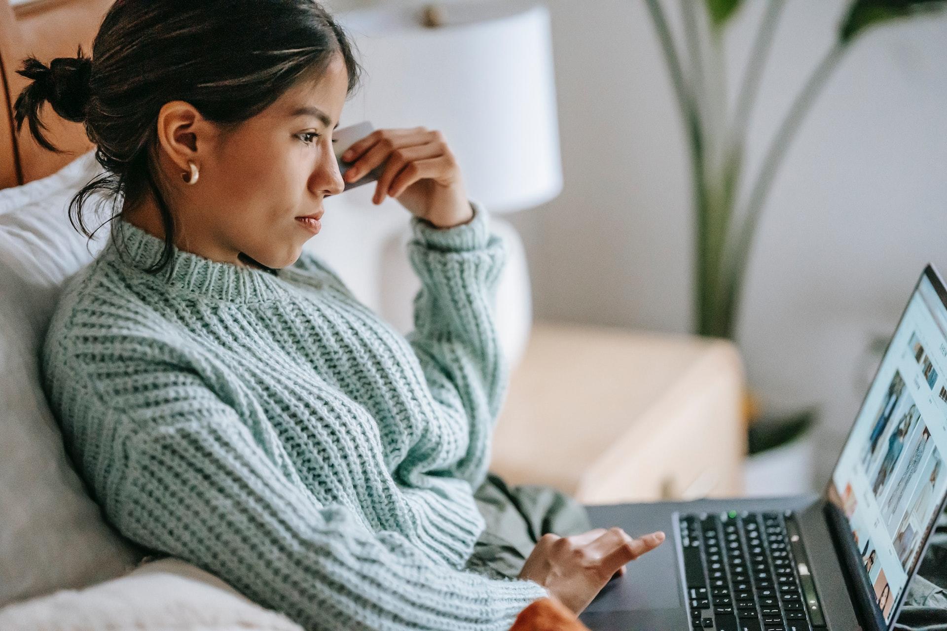 woman on couch on computer searching for piano lessons 