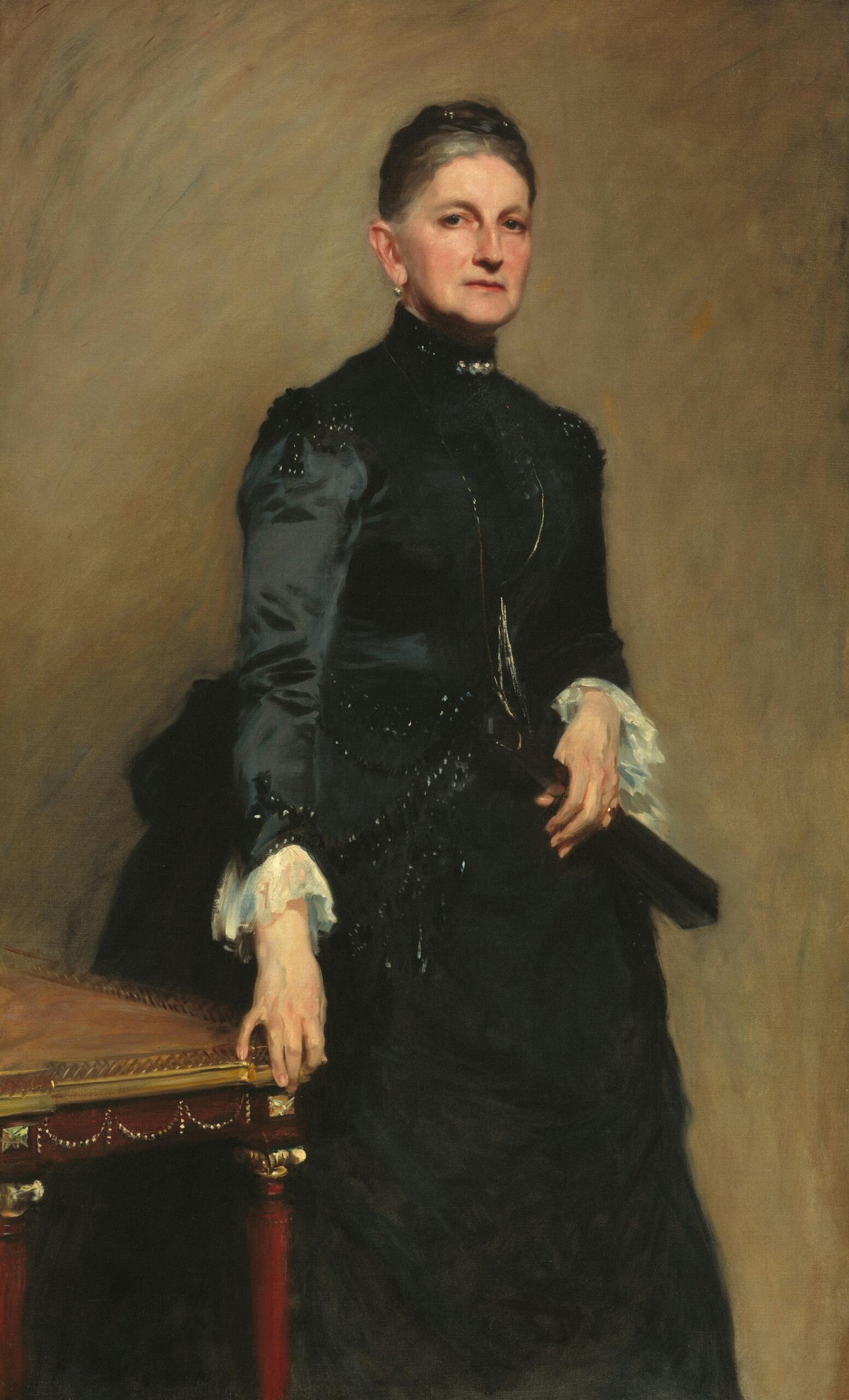 Portrait of a woman in a dark dress, leaning on a table with one hand.