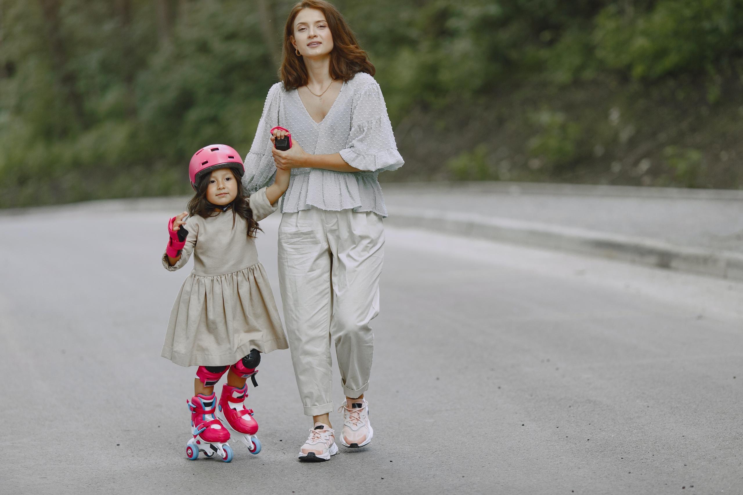 A mother teachers her daughter to roller skate.