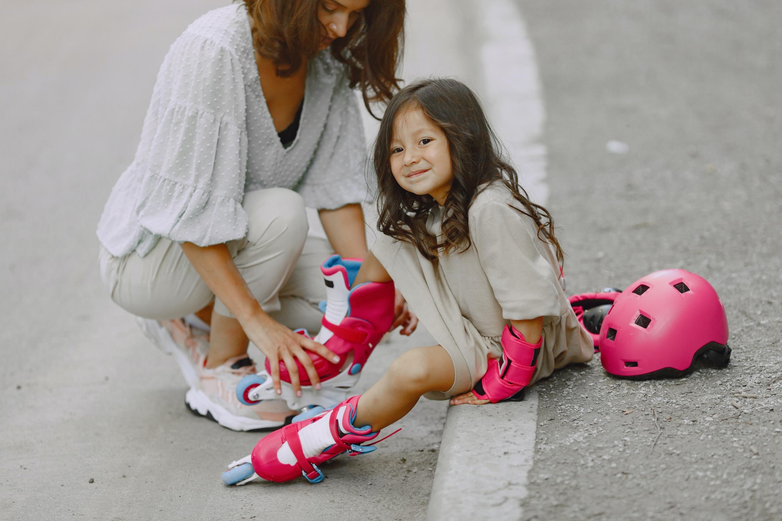 A child sits onthe ground wearing roller blades.