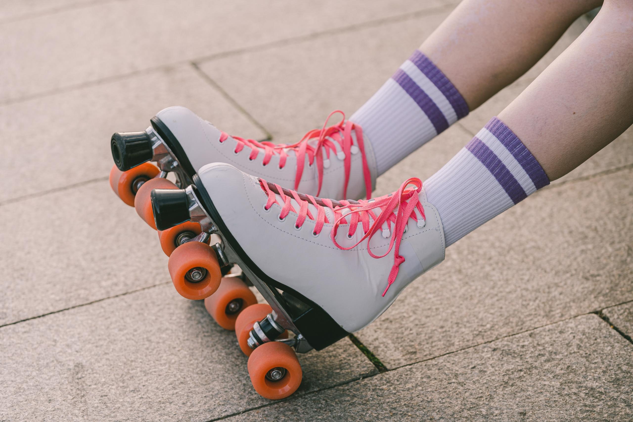 a person sits in pink and white skates