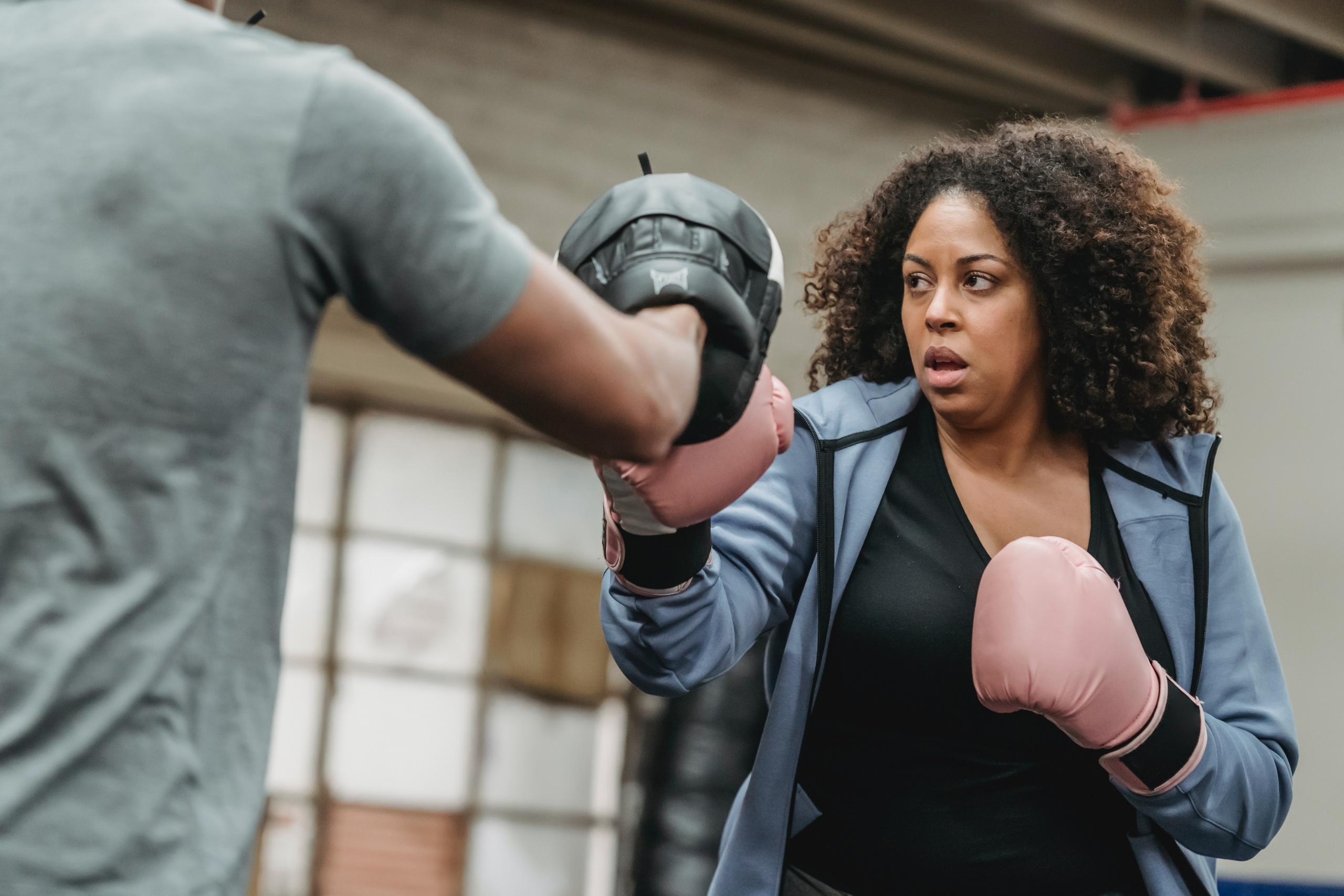 A woman trains with a boxing coach.