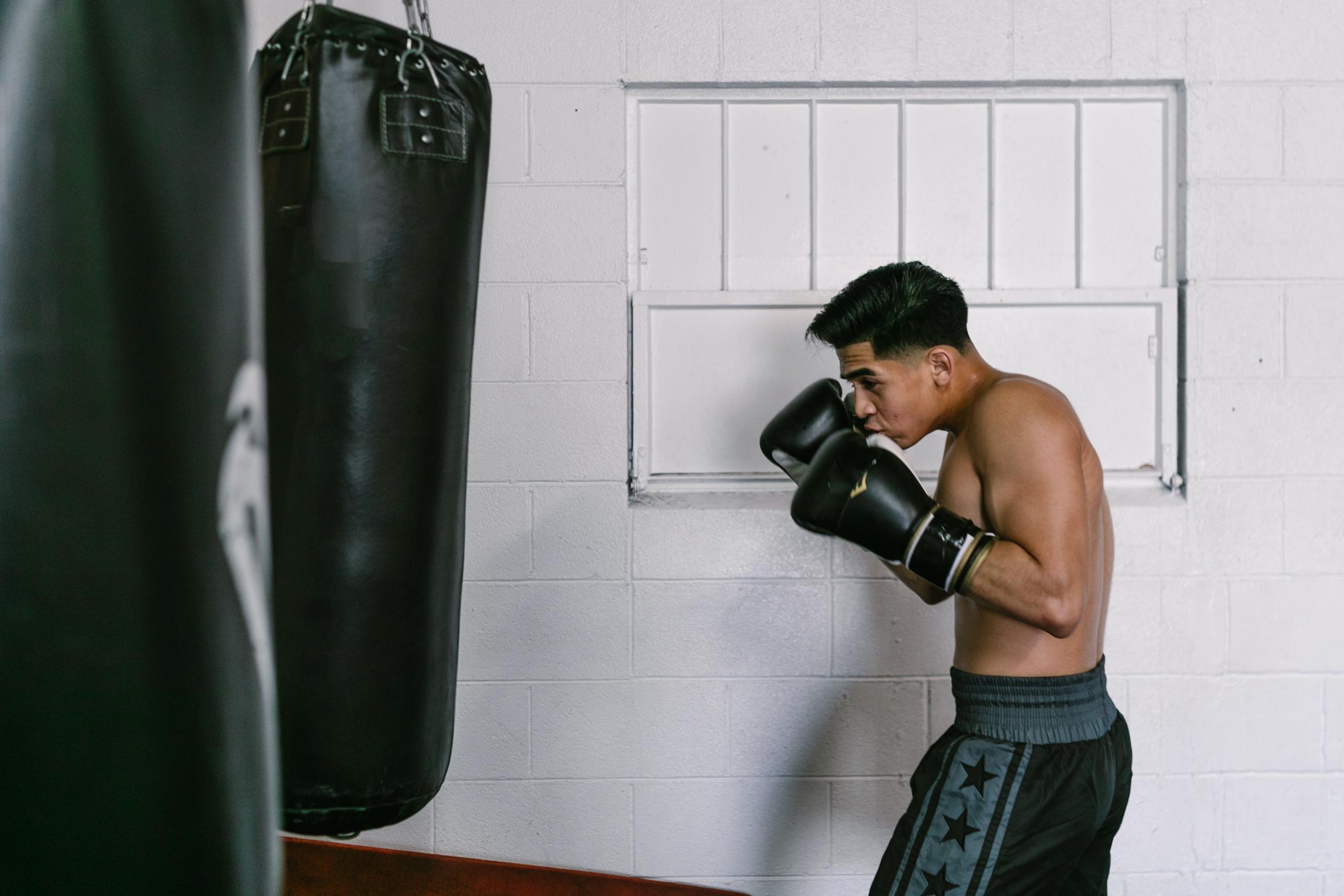 A man prepares to punch a speedbag in a boxing gym.