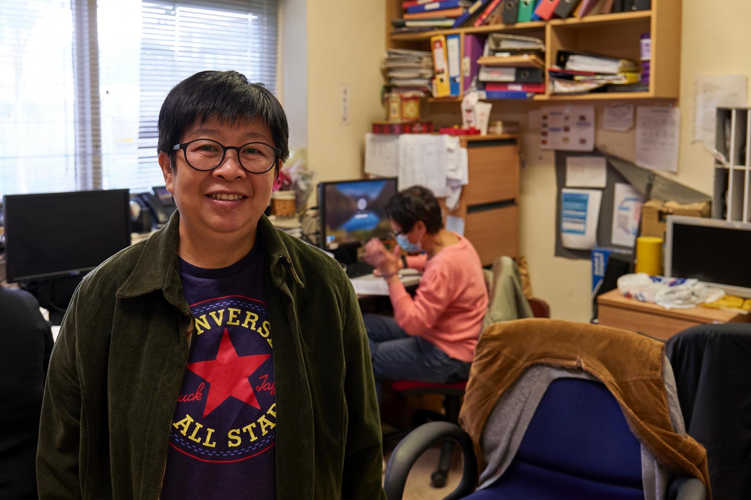 a korean tutor smiling while someone works in the background. 